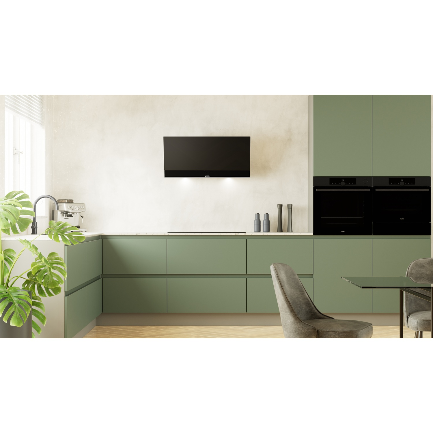 Moderne groene keuken met zwarte ovens, afzuigkap en eettafel.