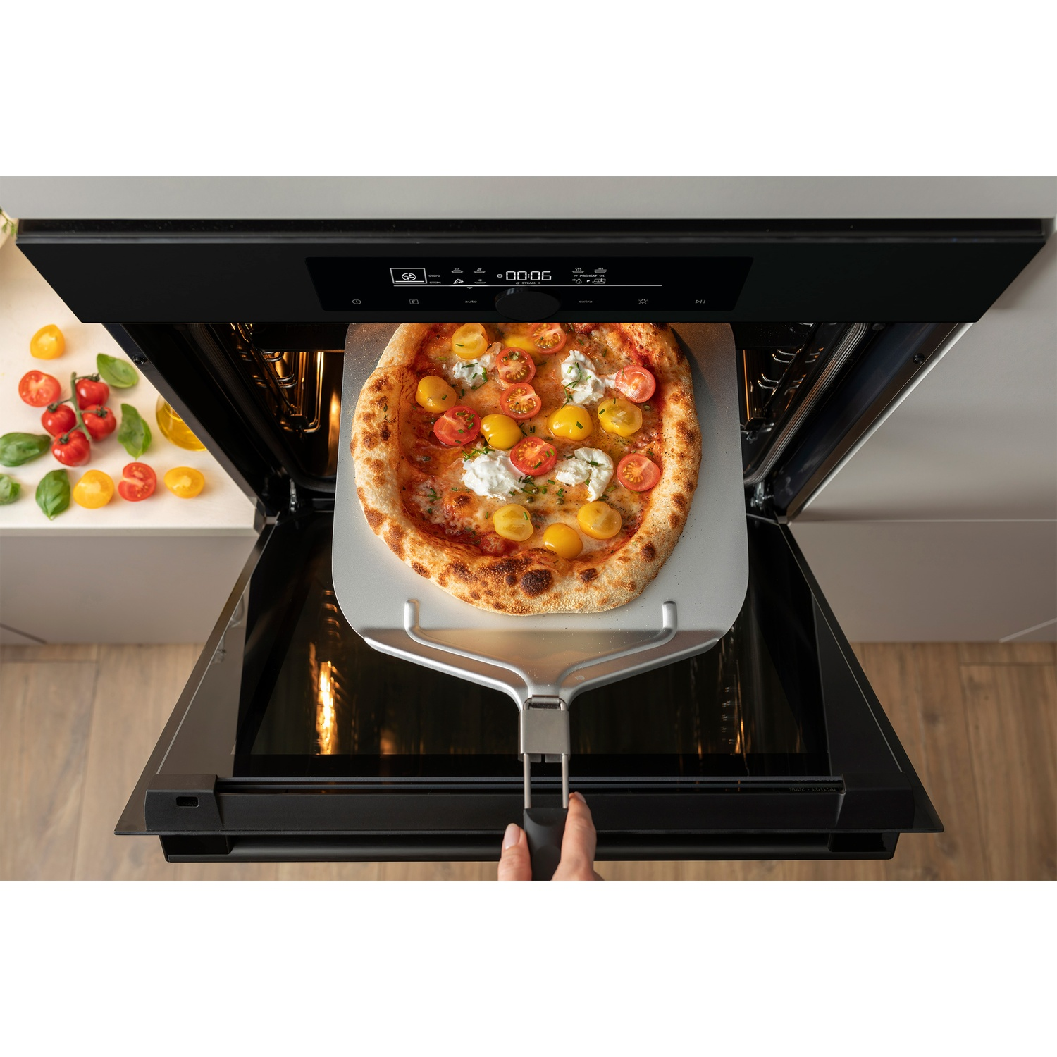 Un four encastré avec une pizza retirée sur une pelle.