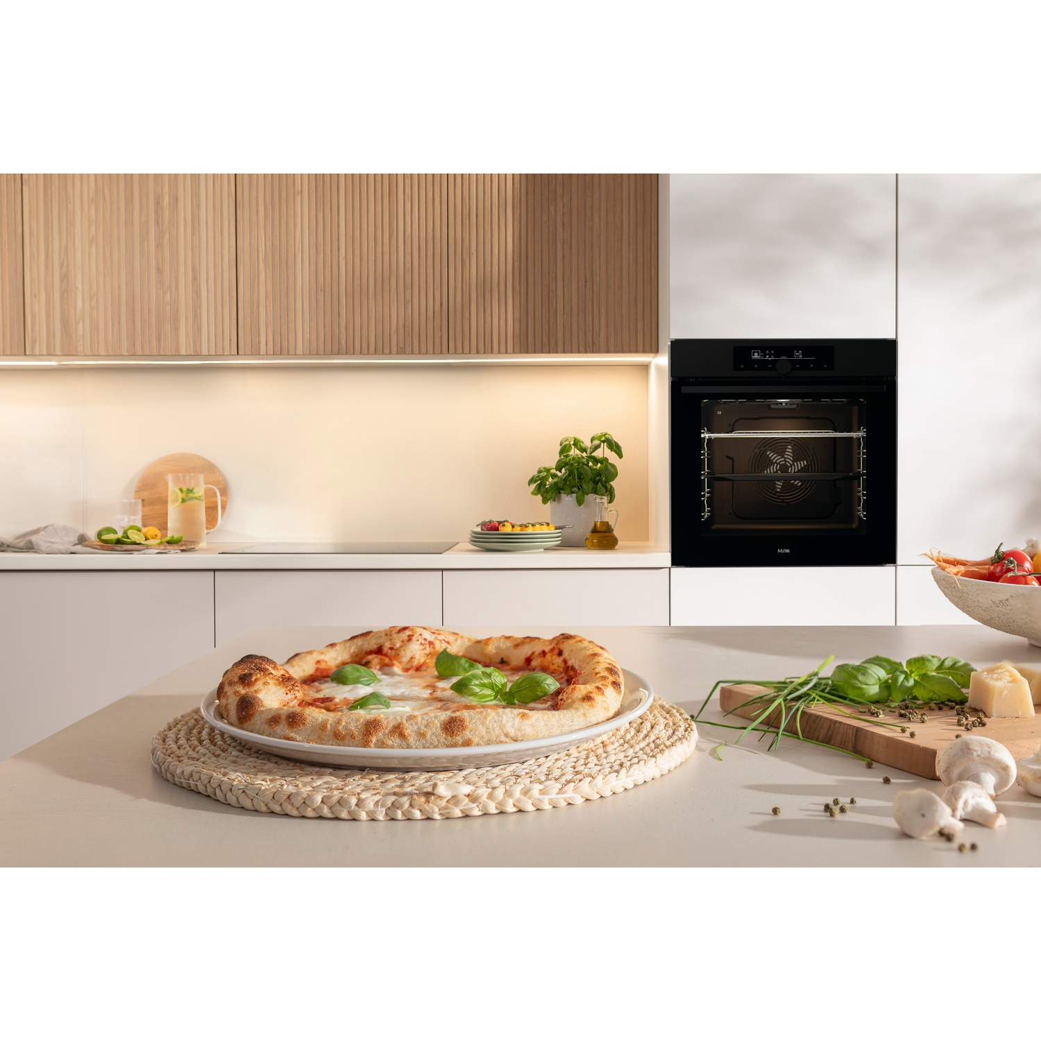 Une pizza sur une assiette à côté d'un four, d'herbes et de champignons.