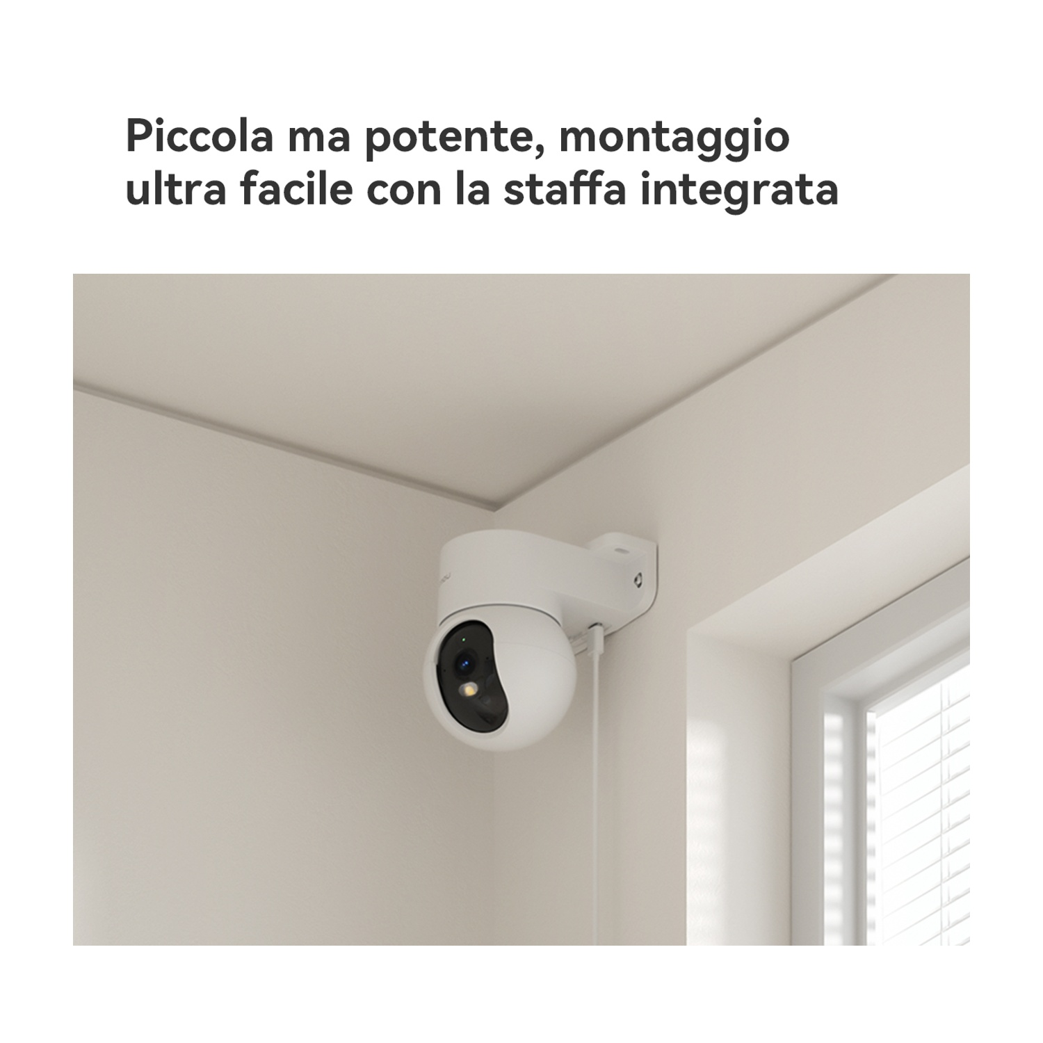 Una telecamera di sicurezza bianca montata a parete, accanto a una finestra con persiane.