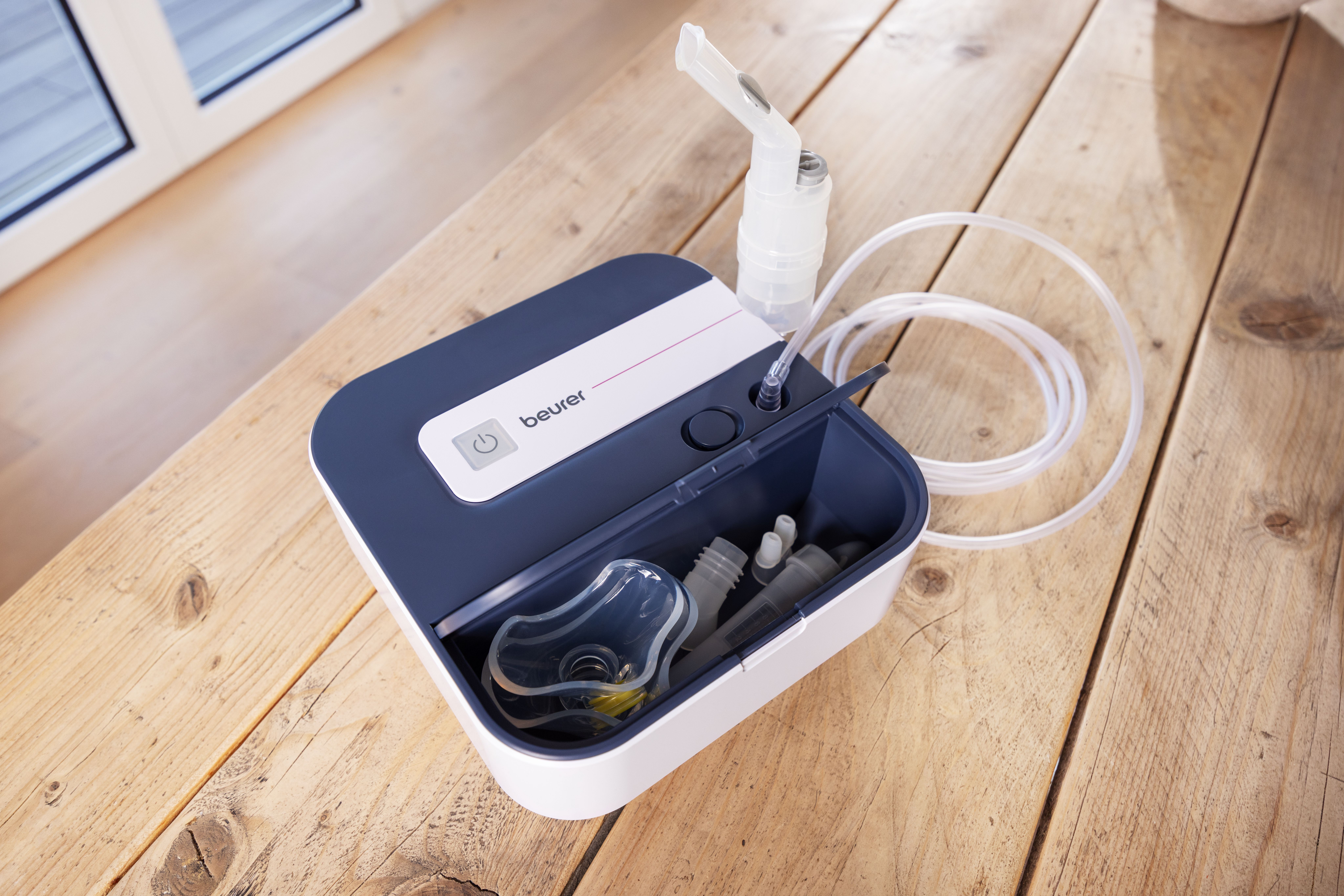 Ein Beurer Inhalator mit Zubehör auf einem Holztisch.
