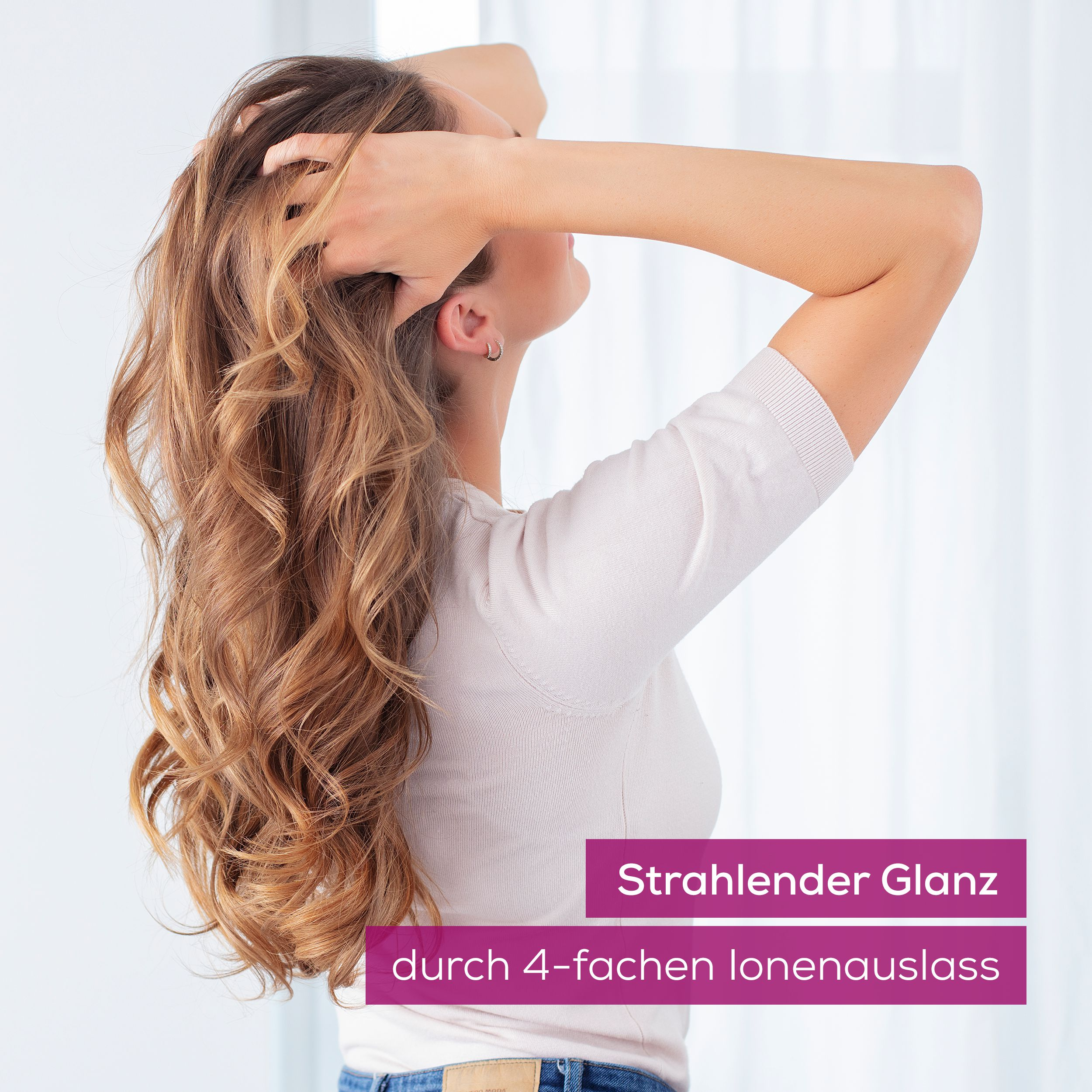 Frau mit langen, welligen Haaren, die sich durch die Haare fährt.