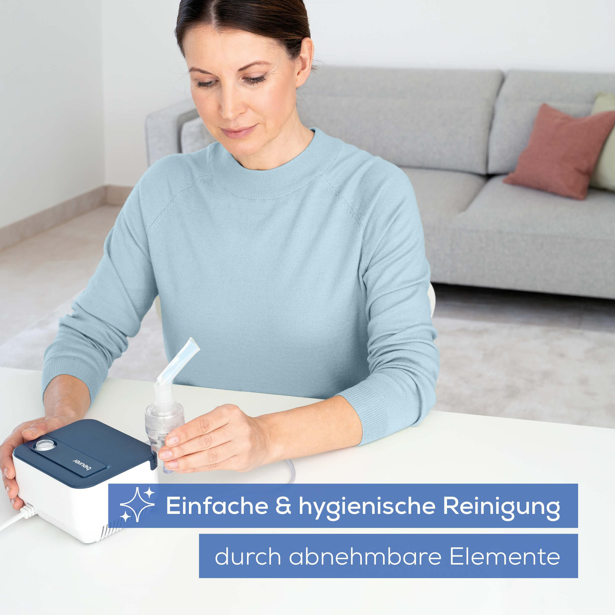 Frau hält Vernebler-Aufsatz, Beurer-Gerät auf Tisch.