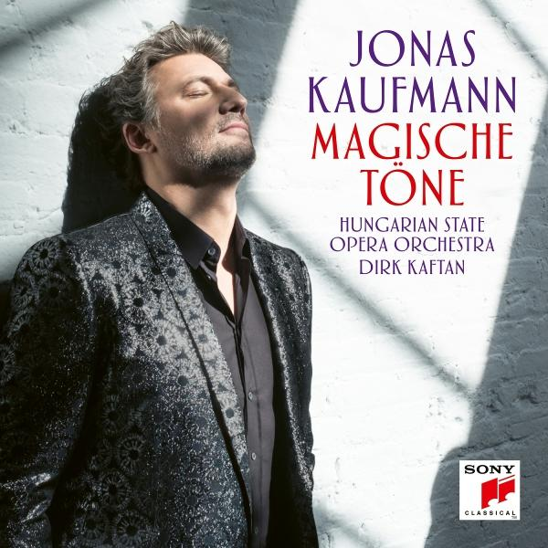 Jonas Kaufmann mit geschlossenen Augen in einem gemusterten Anzug, lehnt an einer Wand.