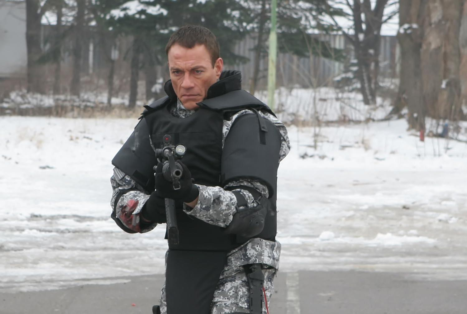 Mann in Schutzkleidung mit Waffe im Schnee.