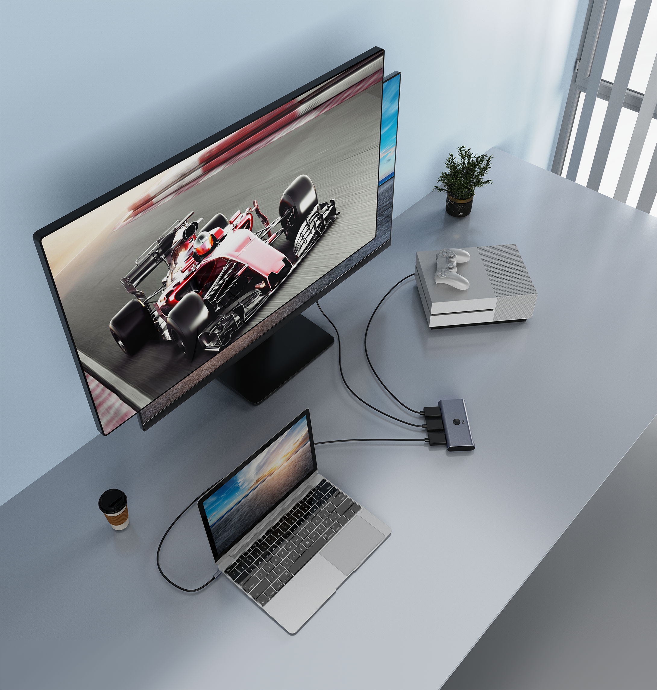 Biurko z monitorem, laptopem, konsolą, kontrolerem, stacją dokującą i kubkiem.