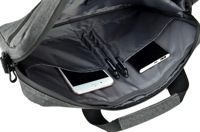 Szara torba z telefonem, powerbankiem i długopisami w kieszeniach.