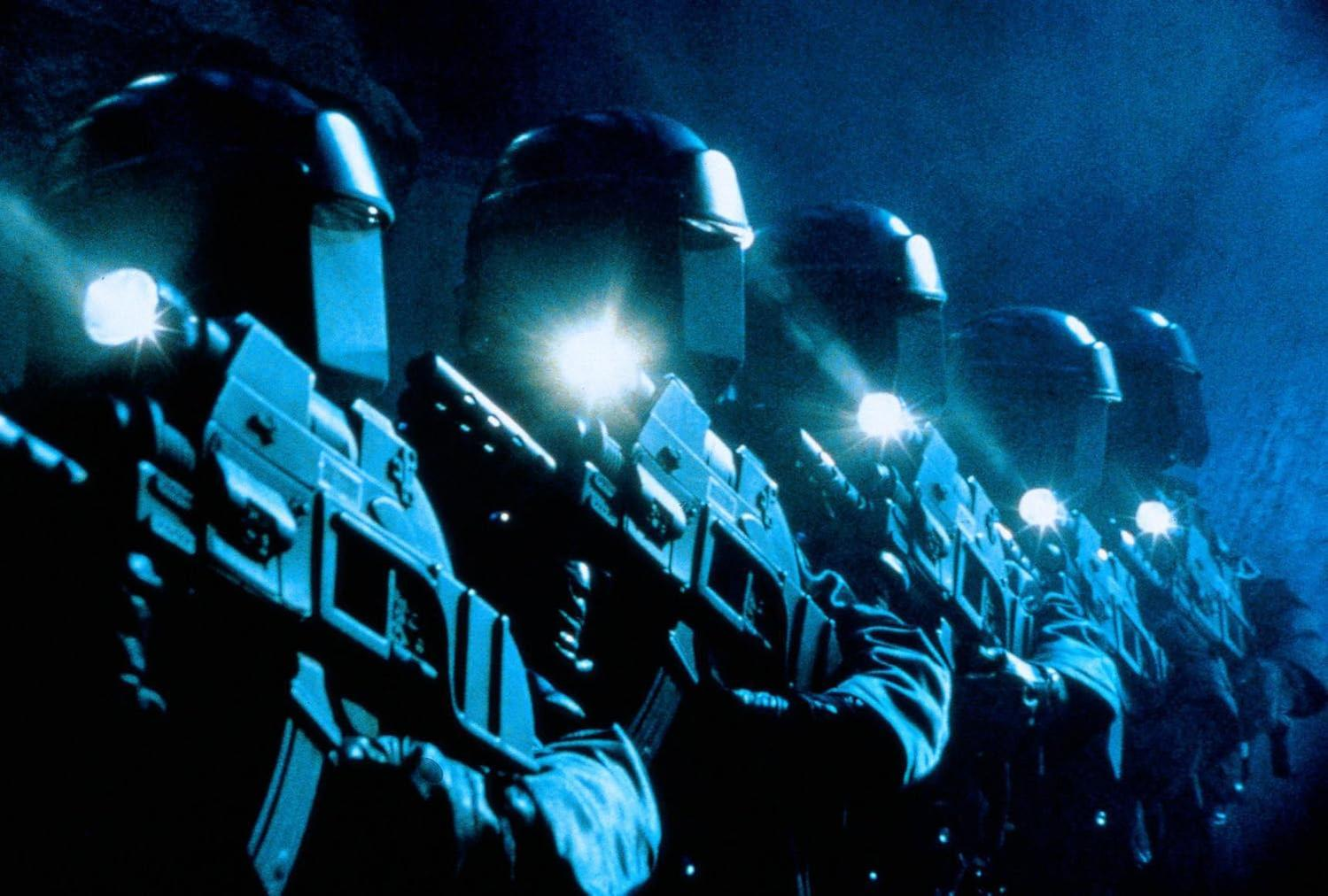 Mehrere Soldaten in blauen Uniformen mit Helmen und Waffen, beleuchtet von Lampen.