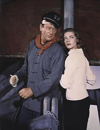 Mann mit Kapitänsmütze und Frau auf einem Schiff. Mann trägt blaues Hemd, Frau helles Oberteil.