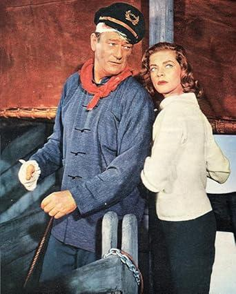 Mann in Kapitänsmütze und Frau in weißem Pullover stehen auf einem Schiff.