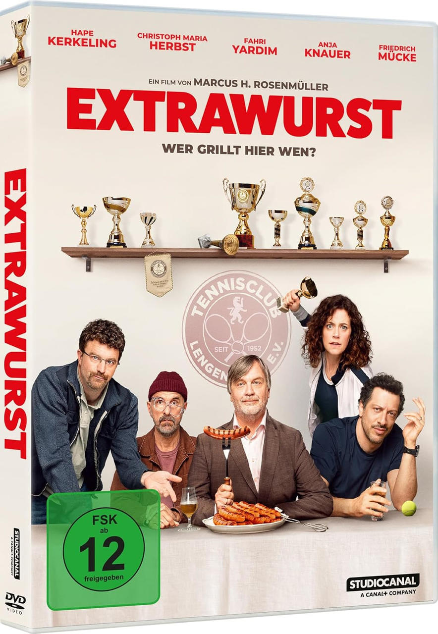 Fünf Personen sitzen an einem Tisch mit Würstchen. Pokale stehen auf einem Regal darüber.