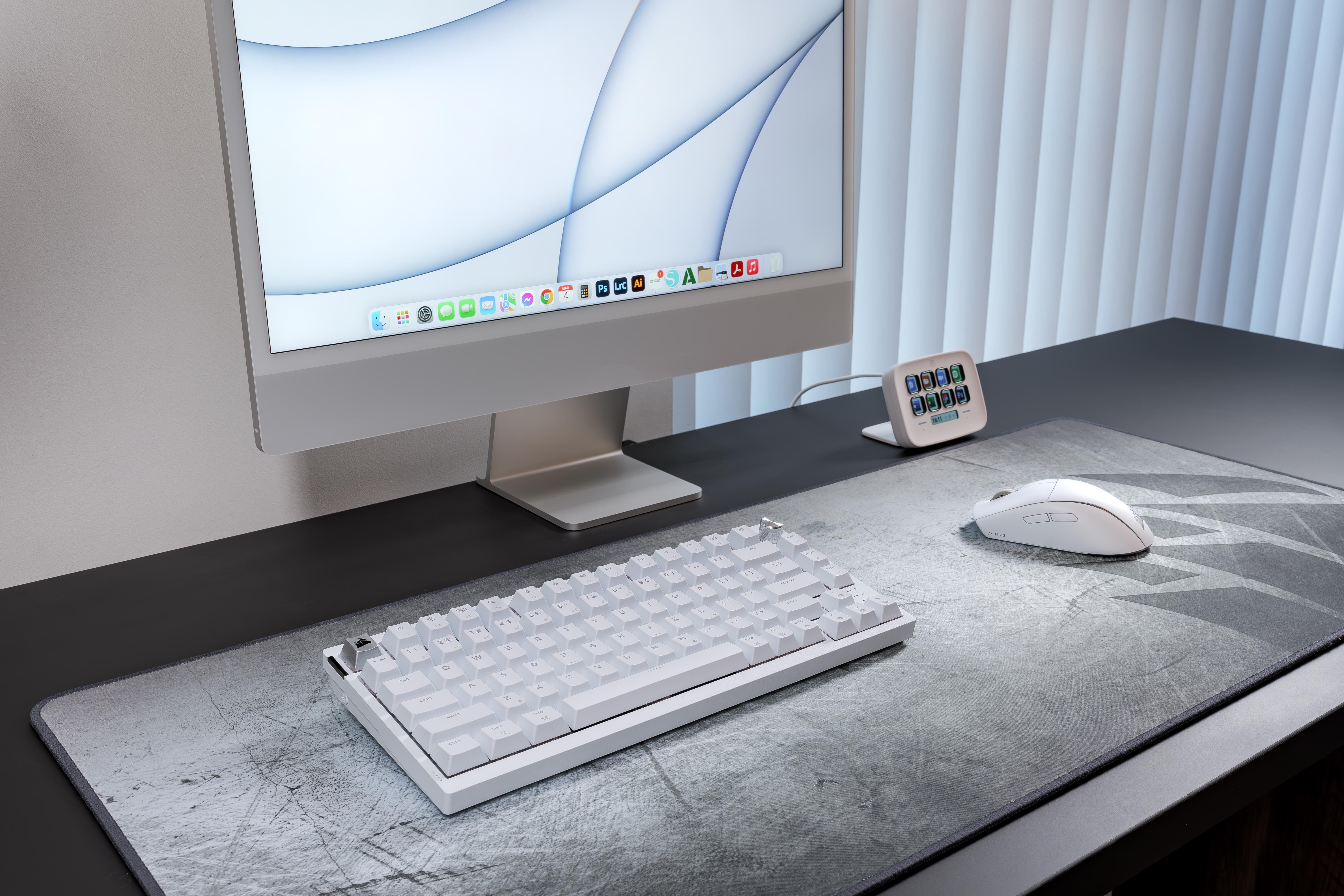 Ein weißes Keyboard, Maus und ein iMac stehen auf einem schwarzen Schreibtisch.