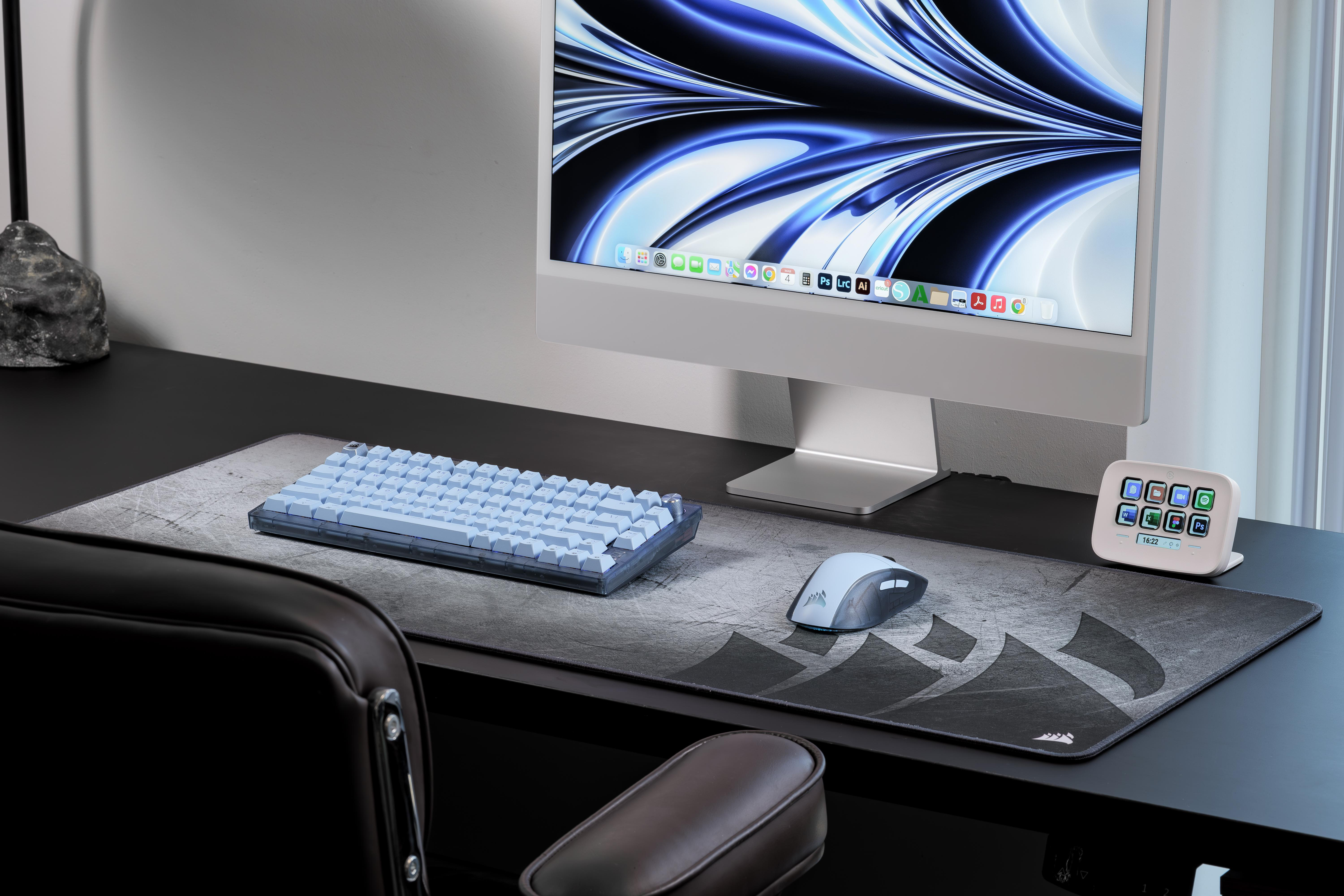 Ein Schreibtisch mit einem blauen Keyboard, einer Maus und einem Monitor mit abstrakter Tapete.