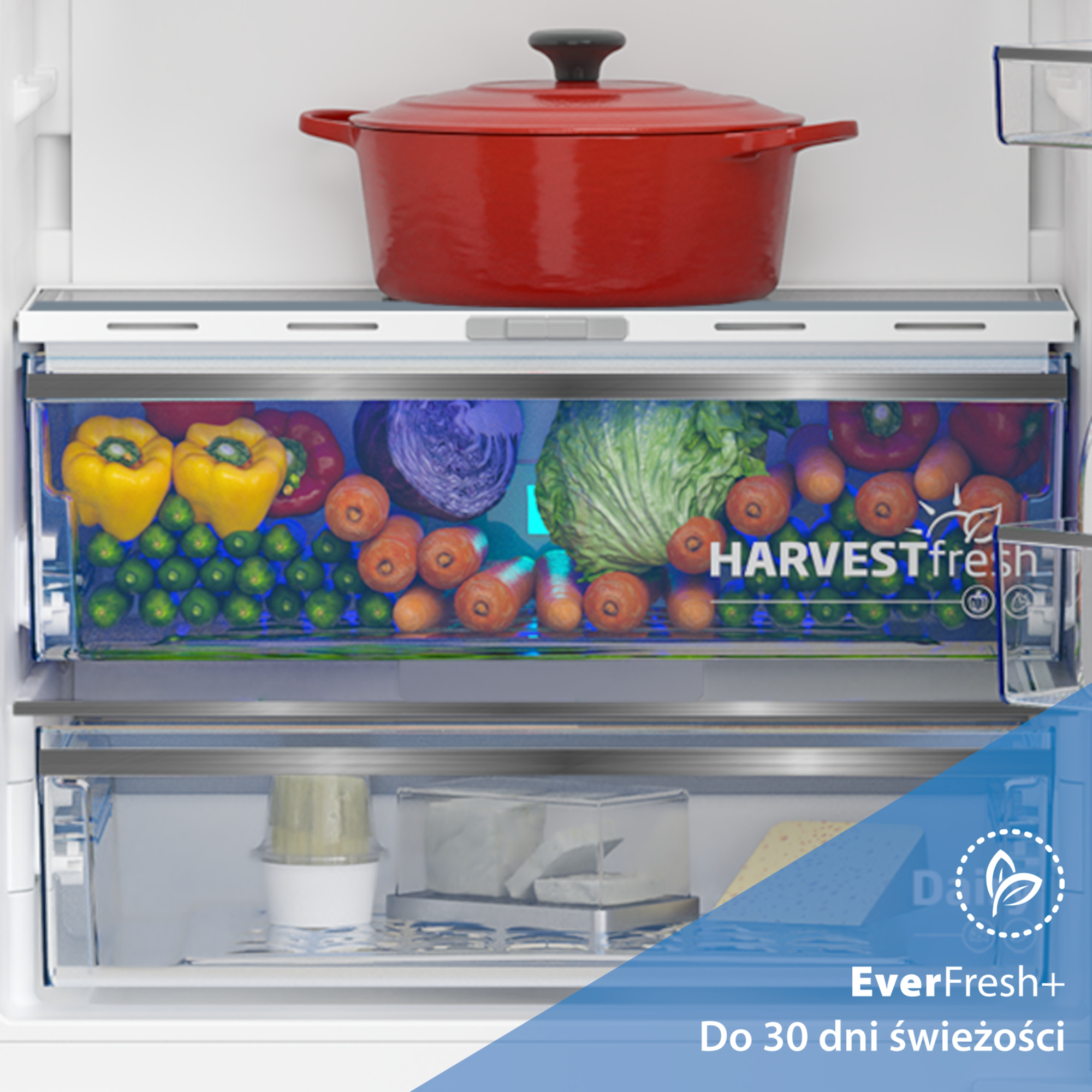 Czerwony garnek na szufladzie lodówki z warzywami.