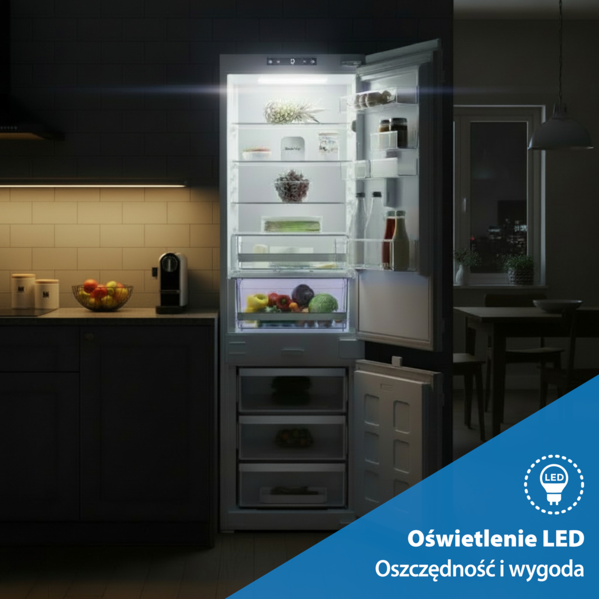 Otwarta lodówka z oświetleniem LED i jedzeniem. Obok kuchnia.