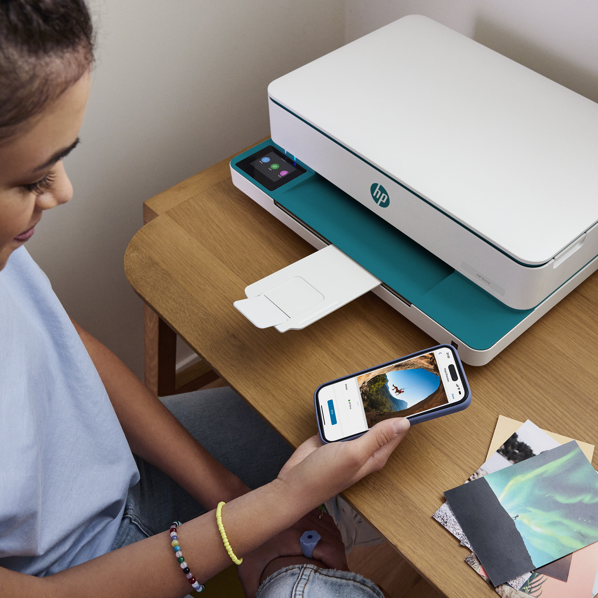 Młoda kobieta obsługuje białą drukarkę i trzyma smartfona.