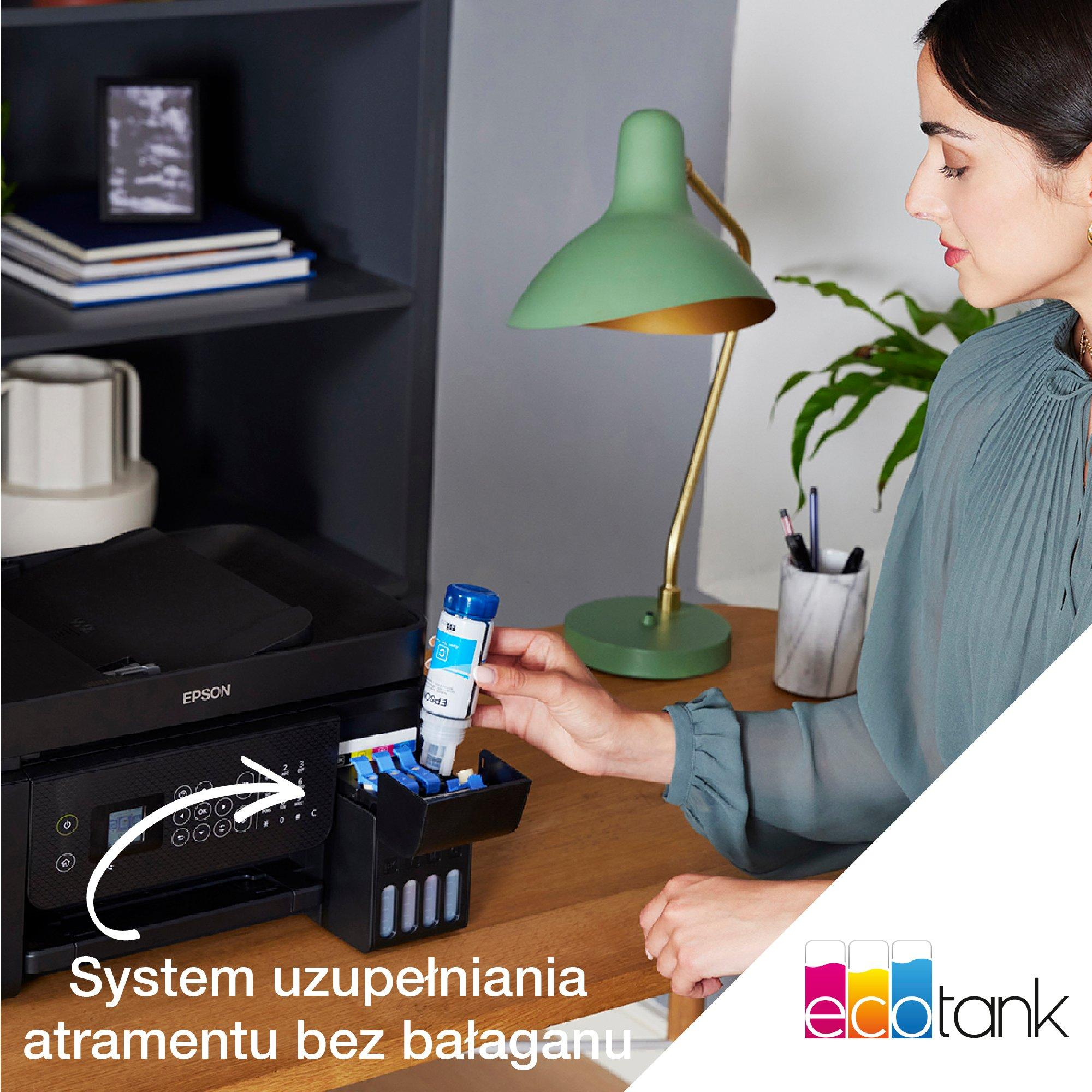 Kobieta uzupełnia tusz do drukarki. Zielona lampa i rośliny w tle.
