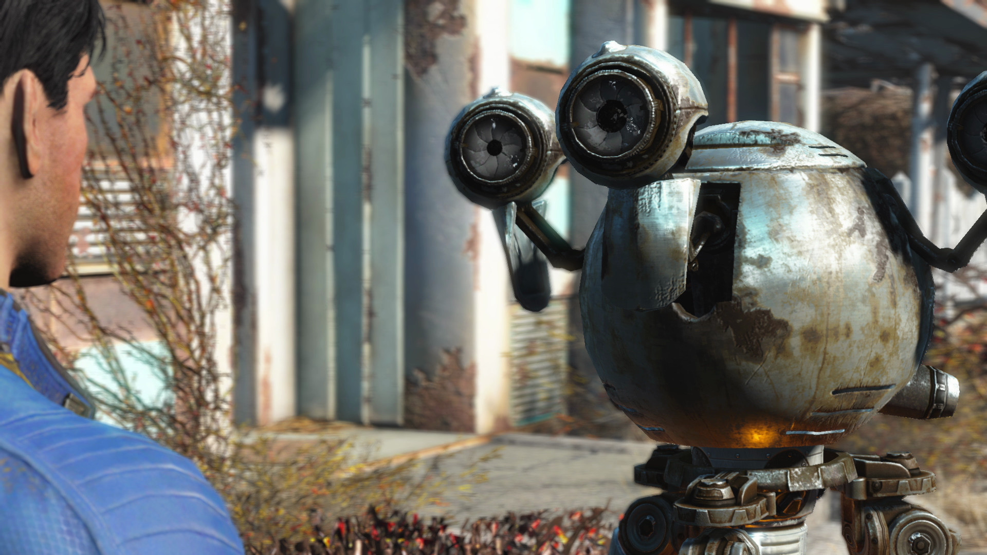 Un uomo in blu guarda un robot arrugginito con grandi occhi.