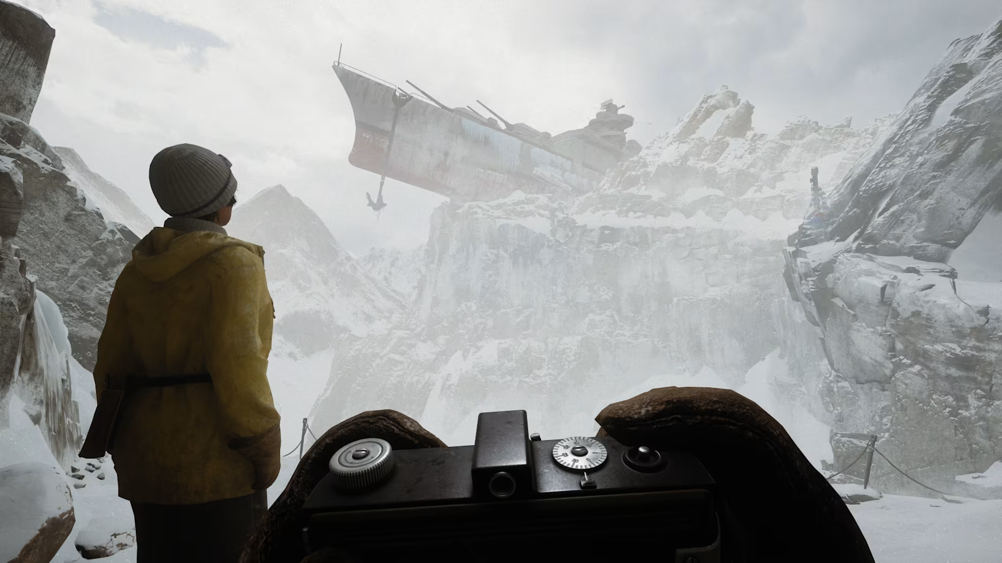 Person in gelber Jacke blickt auf gestrandetes Schiff in verschneiter Berglandschaft.