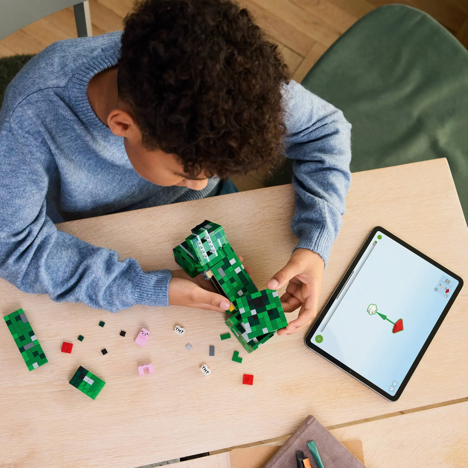 A child builds with green Lego bricks, guided by a tablet.