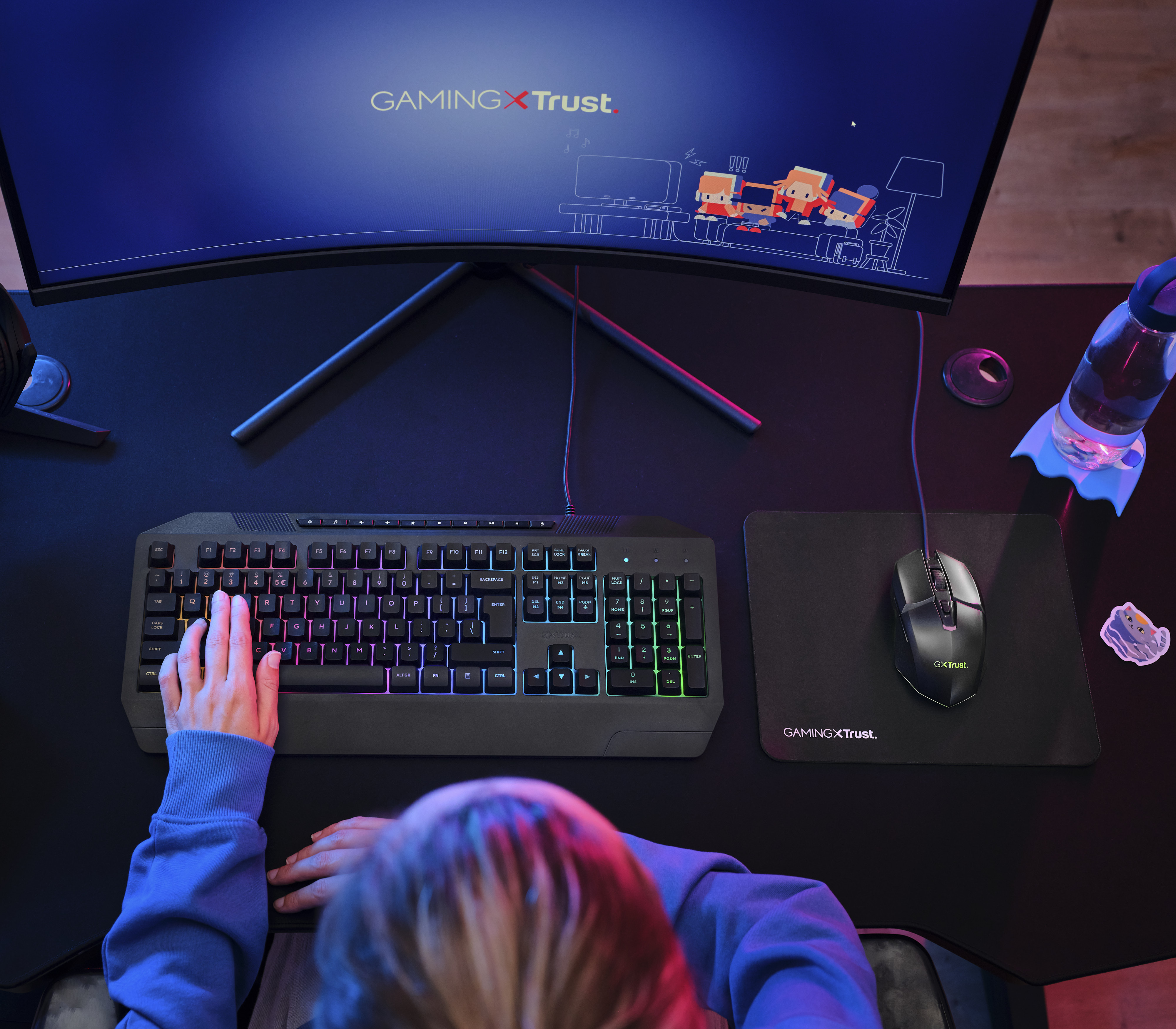 Eine Person spielt an einer Tastatur mit RGB-Beleuchtung, daneben eine Maus und ein Monitor.