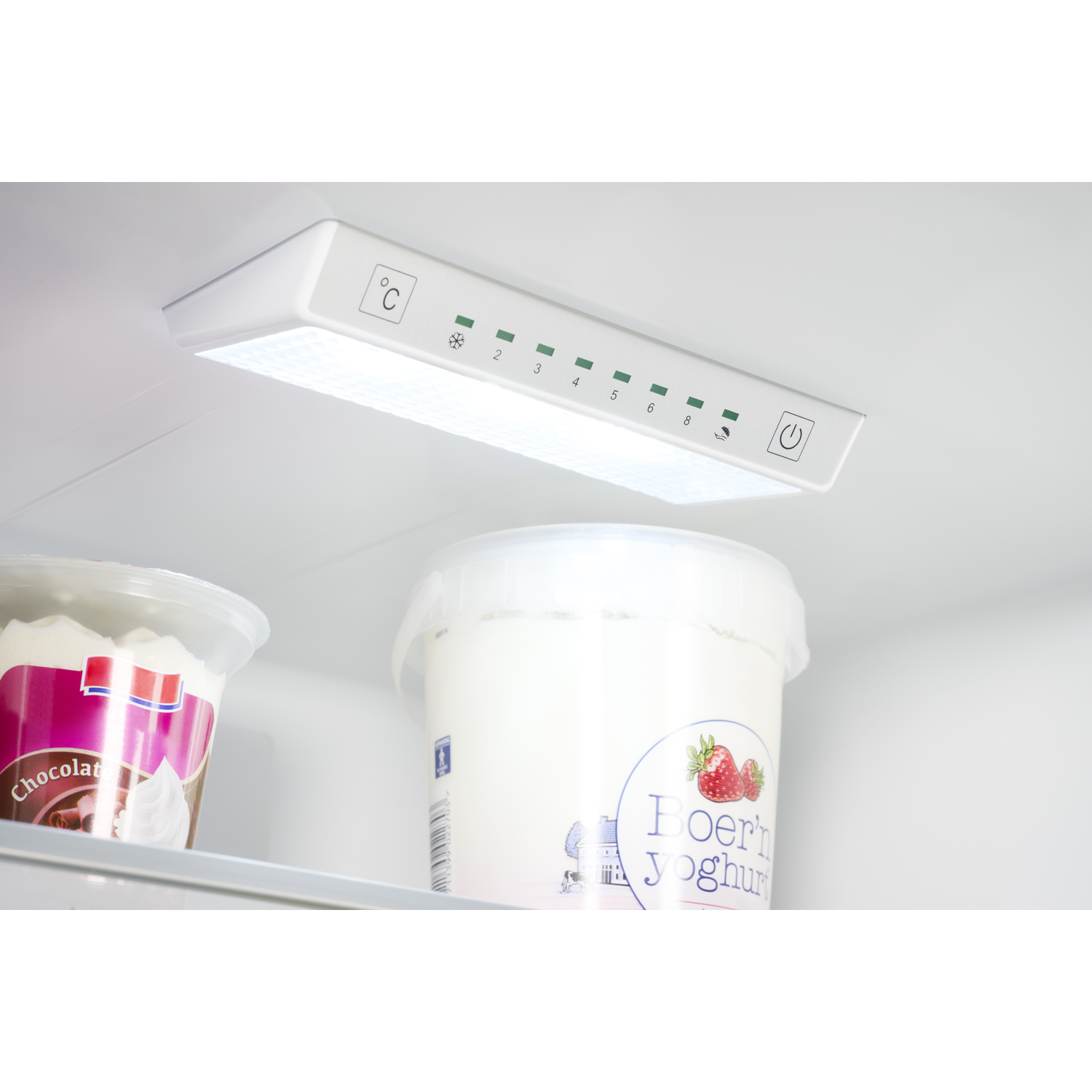 Inside view of a refrigerator with containers of ice cream and yogurt. Control panel above.