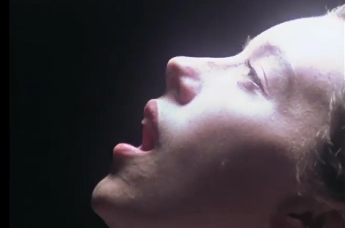 Nahaufnahme eines Gesichts, Augen geschlossen, Mund offen, mit dramatischer Beleuchtung.