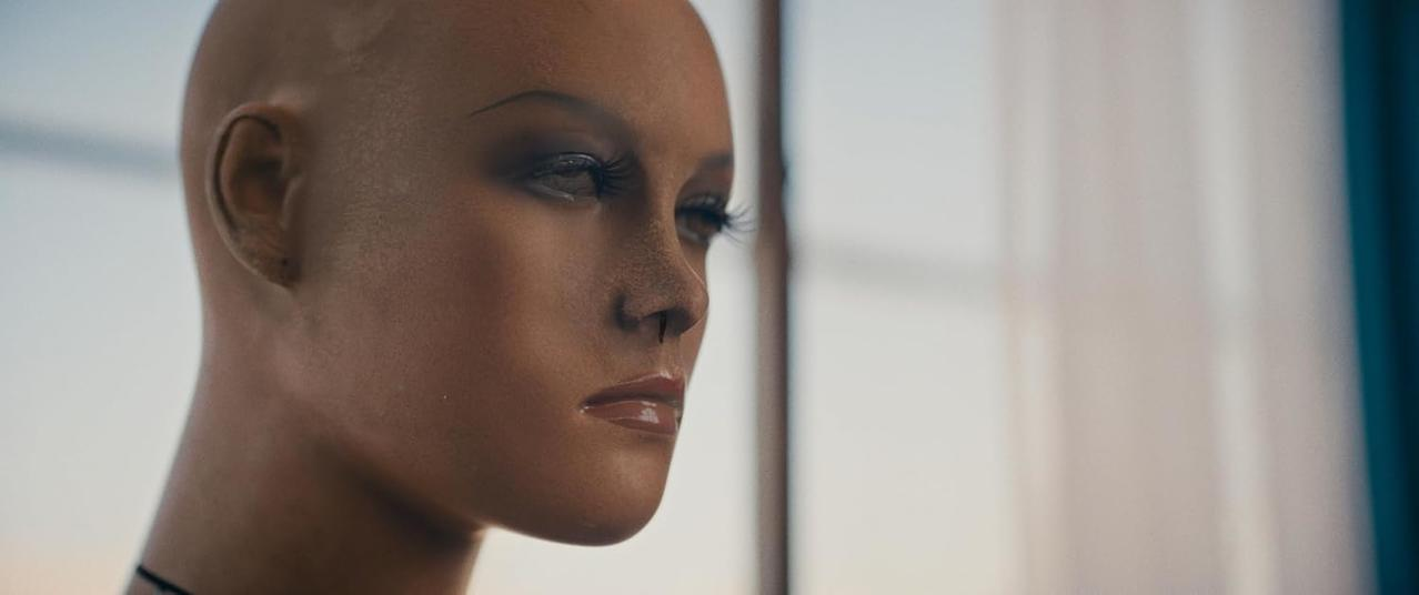 Ein Mannequinkopf mit Make-up blickt nach rechts, mit Fokus auf das Auge und die Lippen.