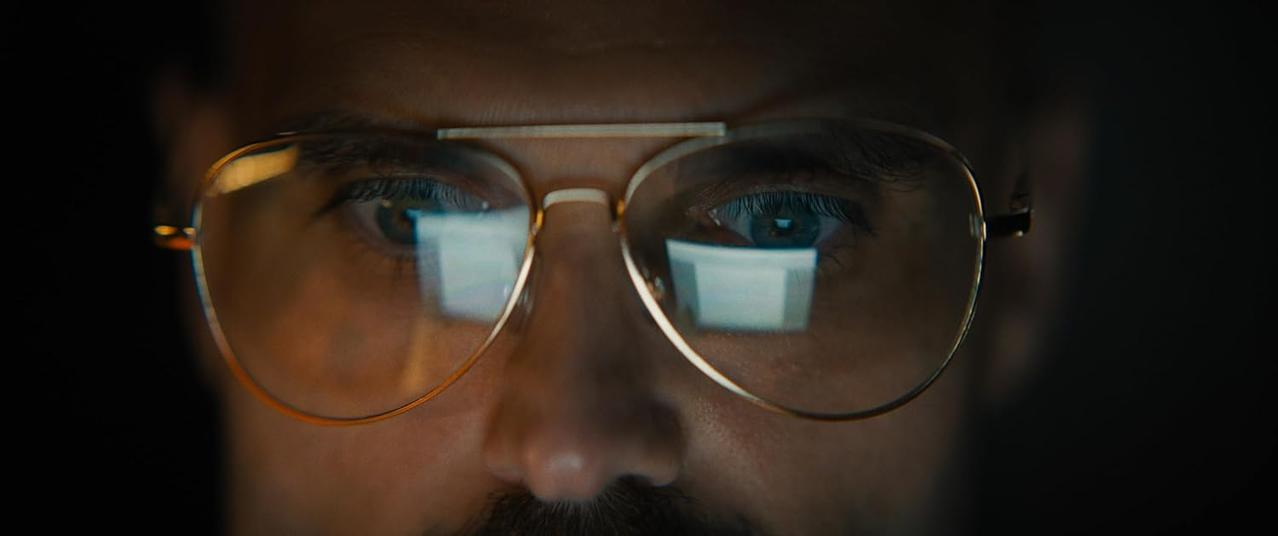 Nahaufnahme eines Auges hinter einer Brille mit Reflexionen.