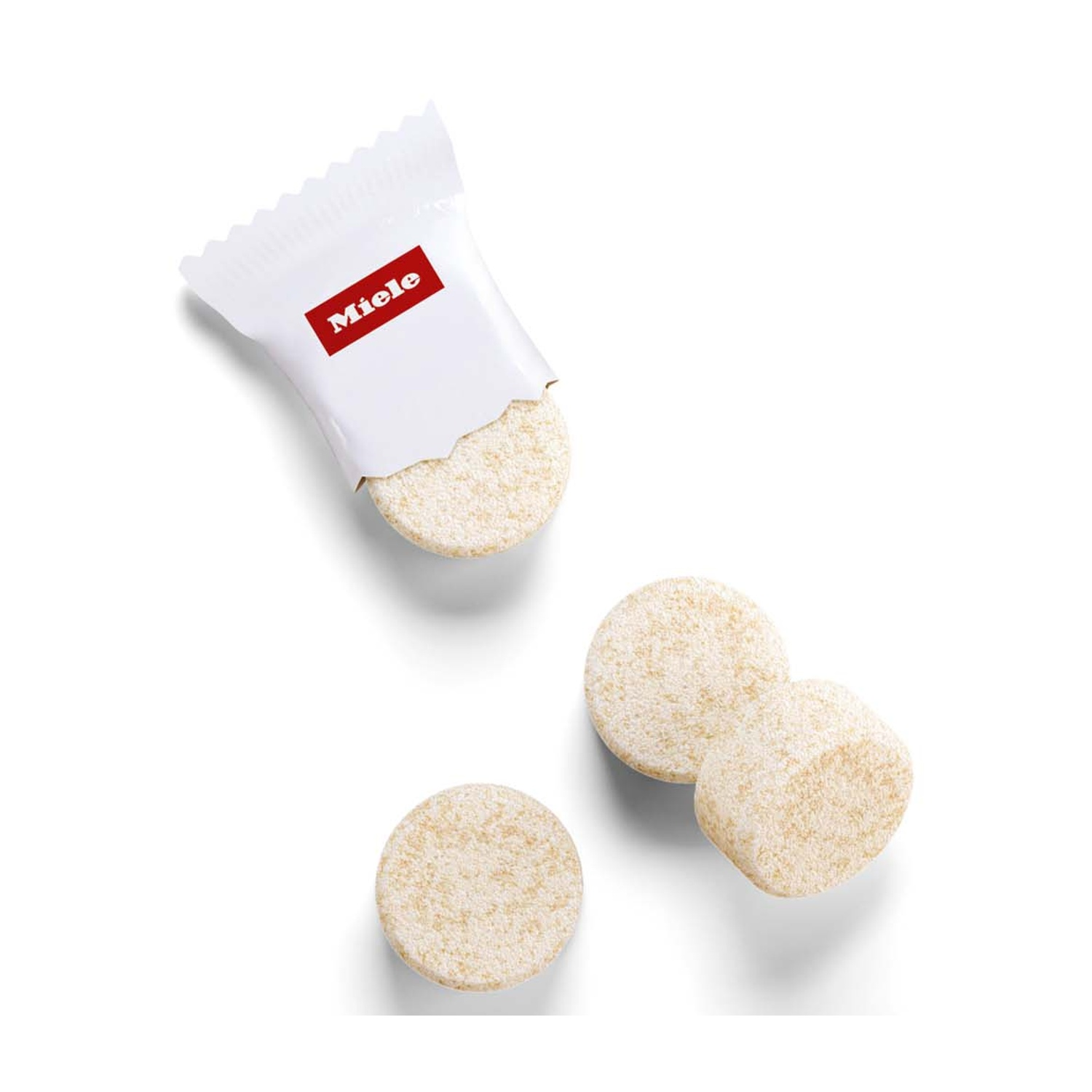 Una confezione di pastiglie detergenti Miele e tre pastiglie su sfondo bianco.