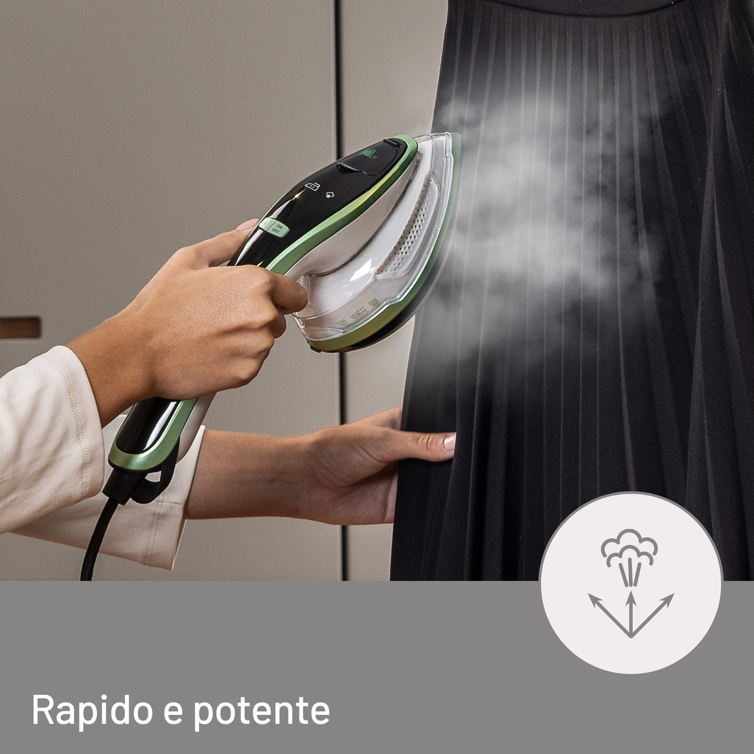 Una mano tiene un ferro da stiro a vapore puntato su un capo nero a pieghe.