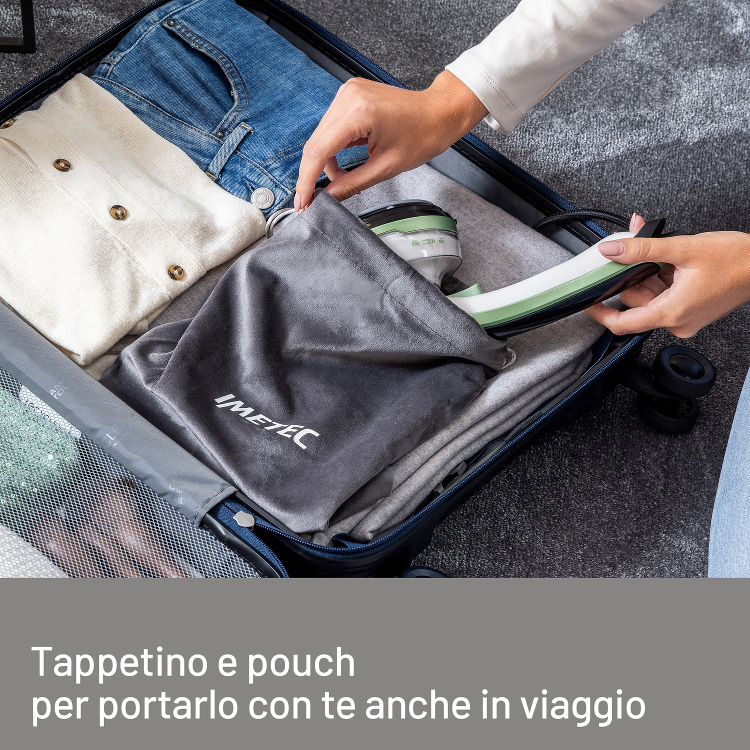 Persona che sistema vestiti e un accessorio in una valigia. Una pochette grigia è nella valigia.