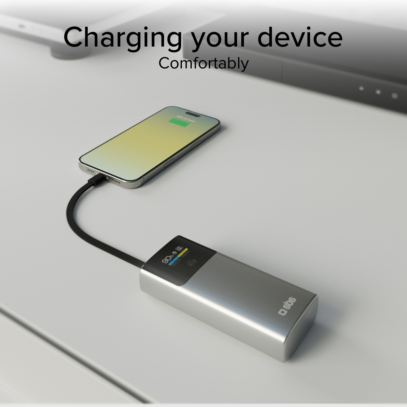 Ein silbernes Powerbank lädt ein Smartphone auf dem Schreibtisch.