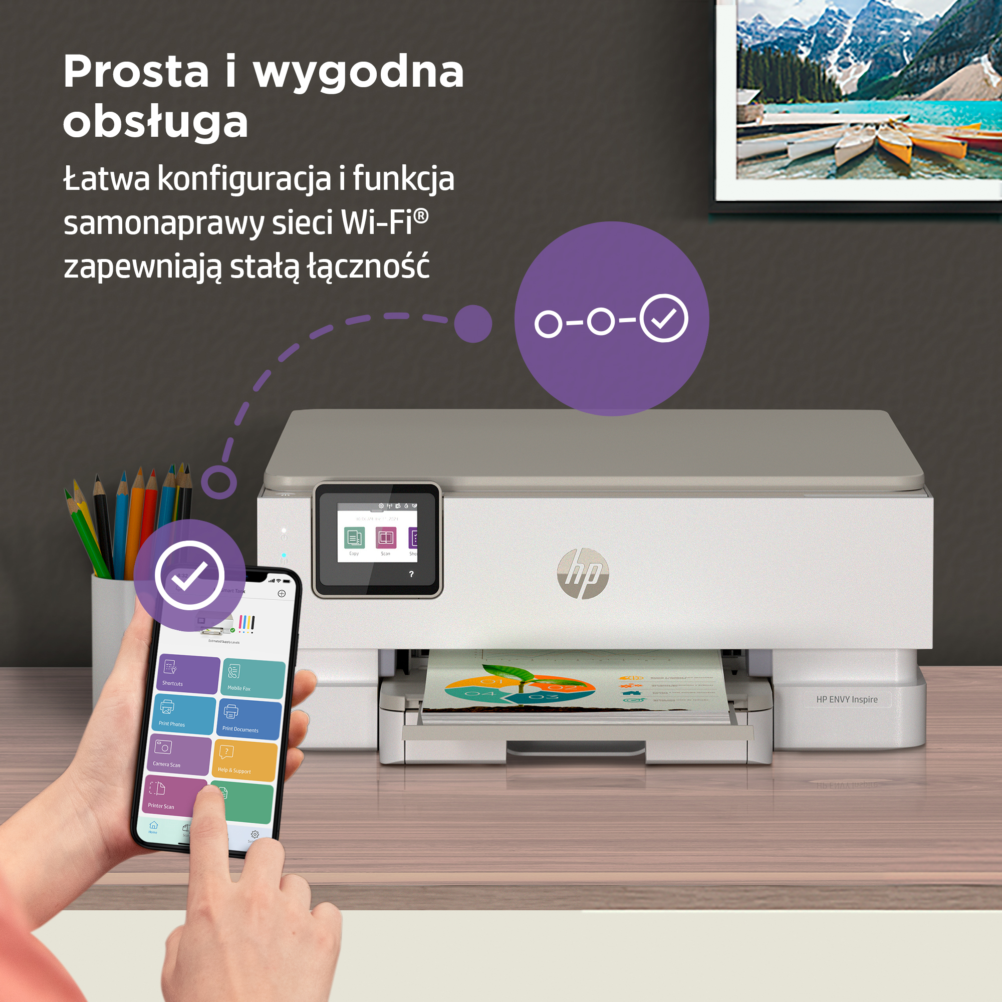 Drukarka HP ze smartfonem pokazującym aplikację. Kredki w szklance. Krajobraz górski.