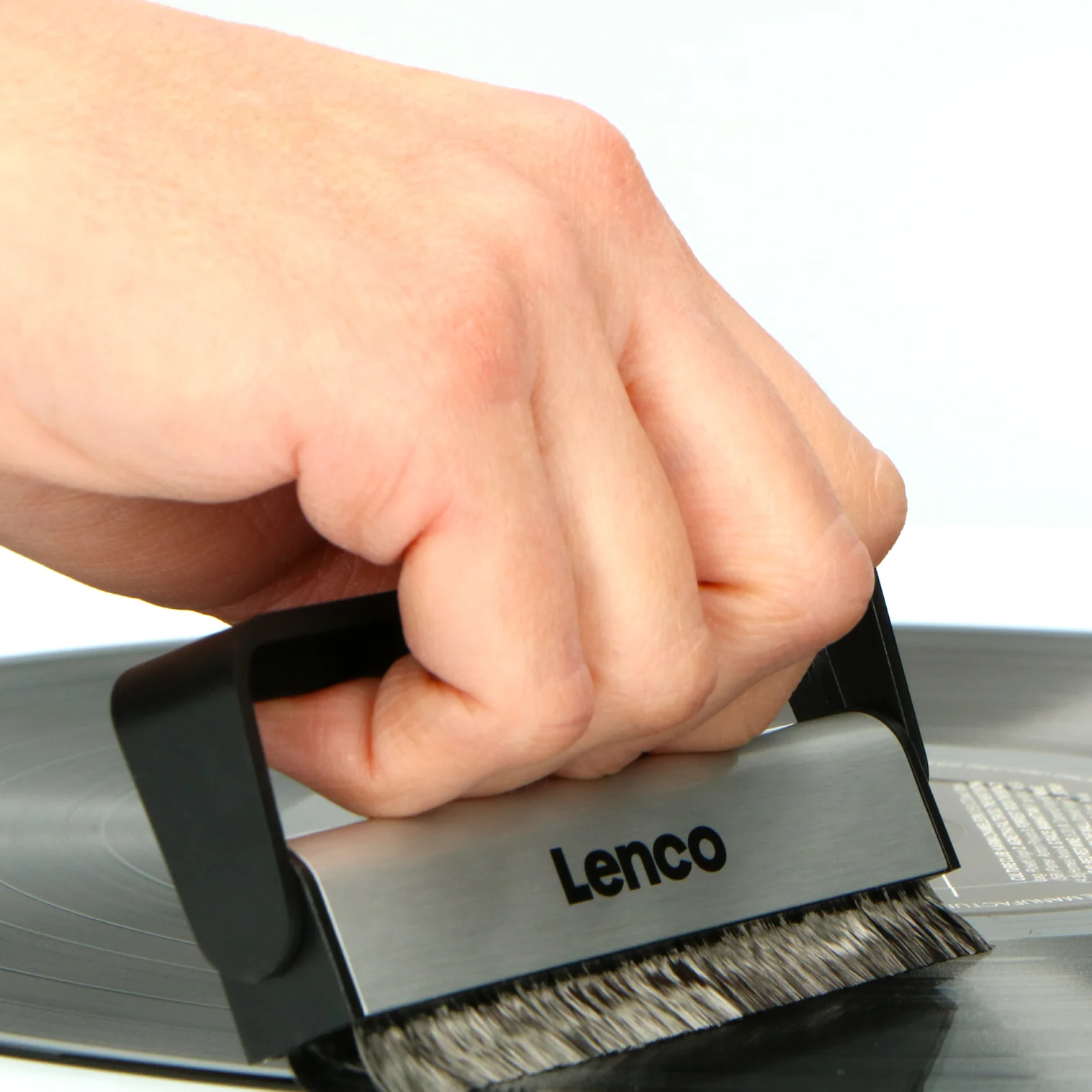 Eine Hand hält einen Lenco-Plattenreiniger auf einer Schallplatte.