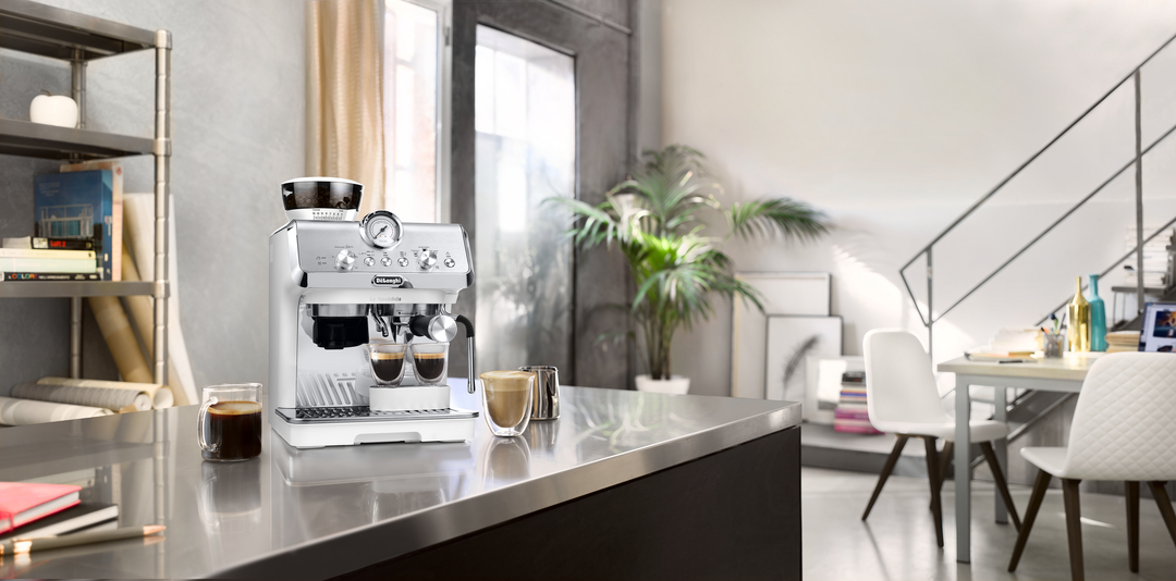 Eine weiße Espressomaschine mit zwei Tassen Espresso auf einer Arbeitsplatte.