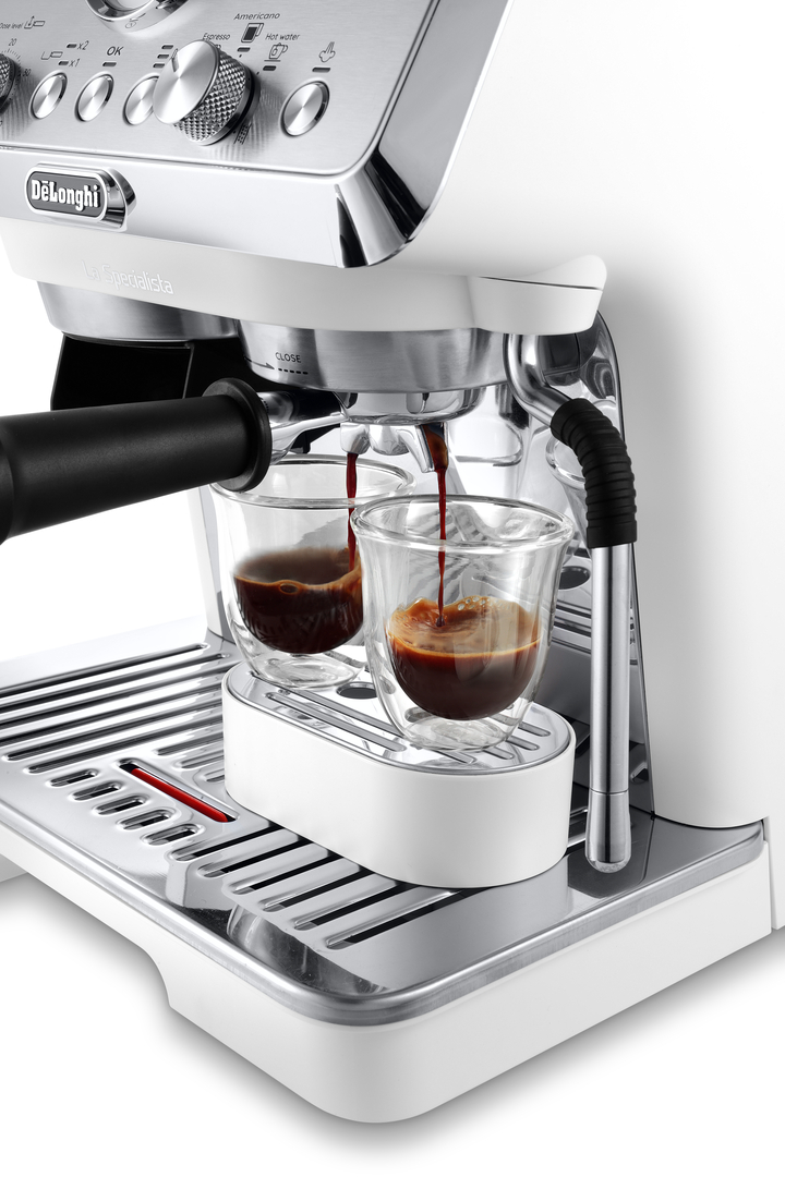 Eine Espressomaschine brüht Kaffee in zwei Gläser. Chromdetails und weiße Oberflächen.