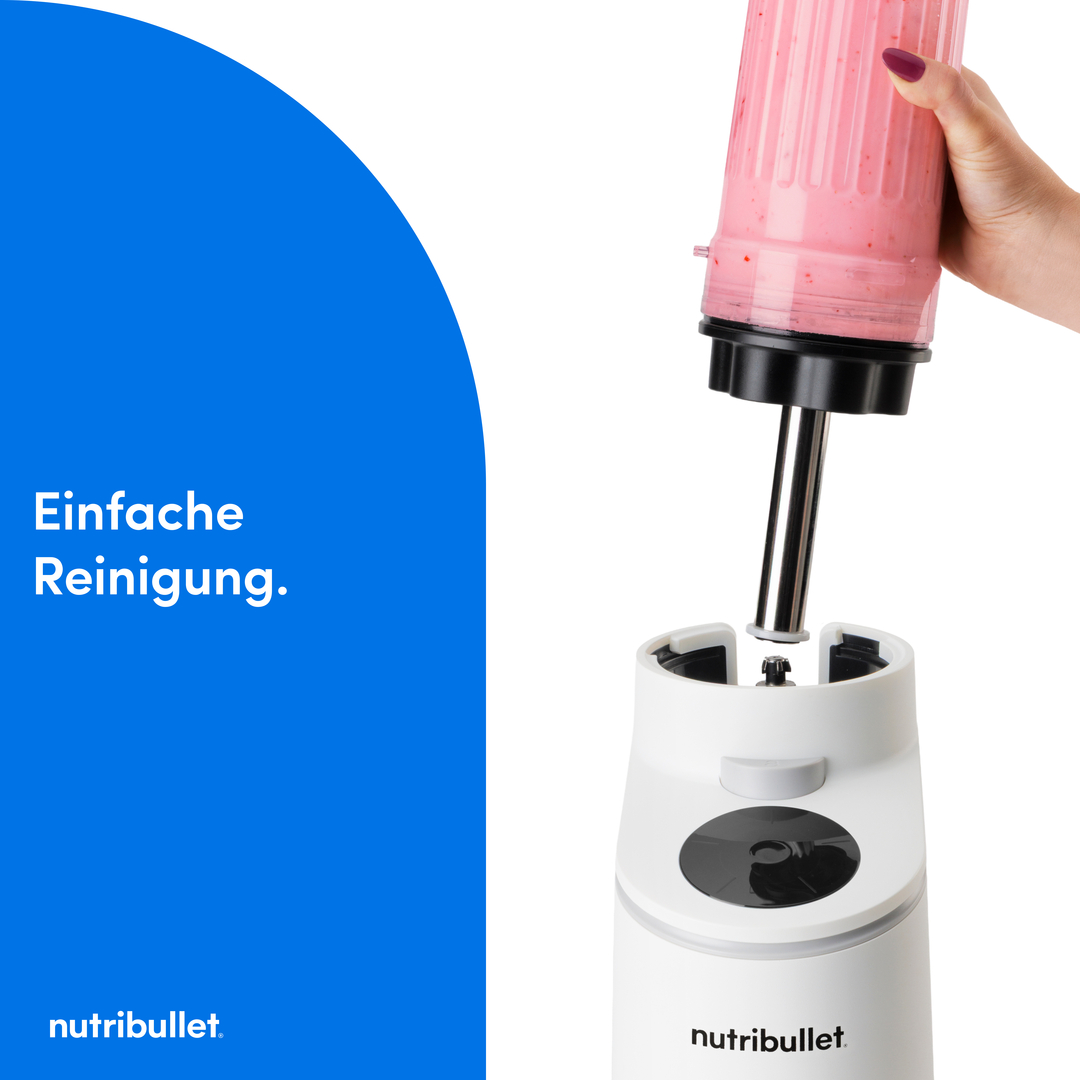 Eine Hand hält einen Becher mit rosa Smoothie über eine weiße Nutribullet Basis.