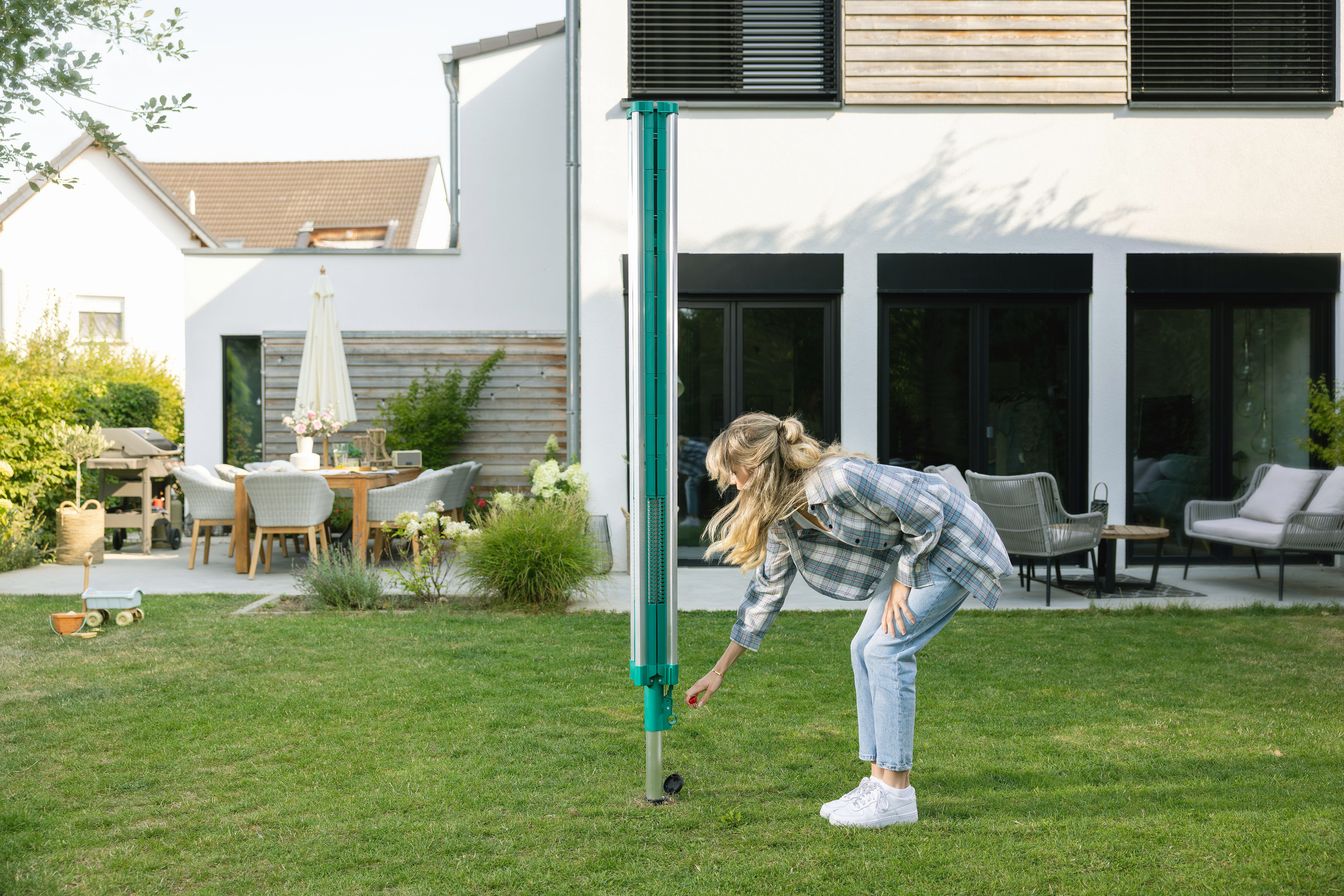Eine Frau im Garten interagiert mit einer grünen Stange im Gras.