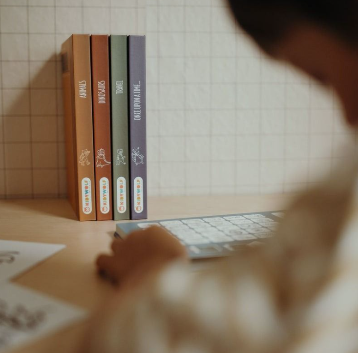 Vier Kinderbücher stehen nebeneinander auf einem Schreibtisch mit einer Tastatur.