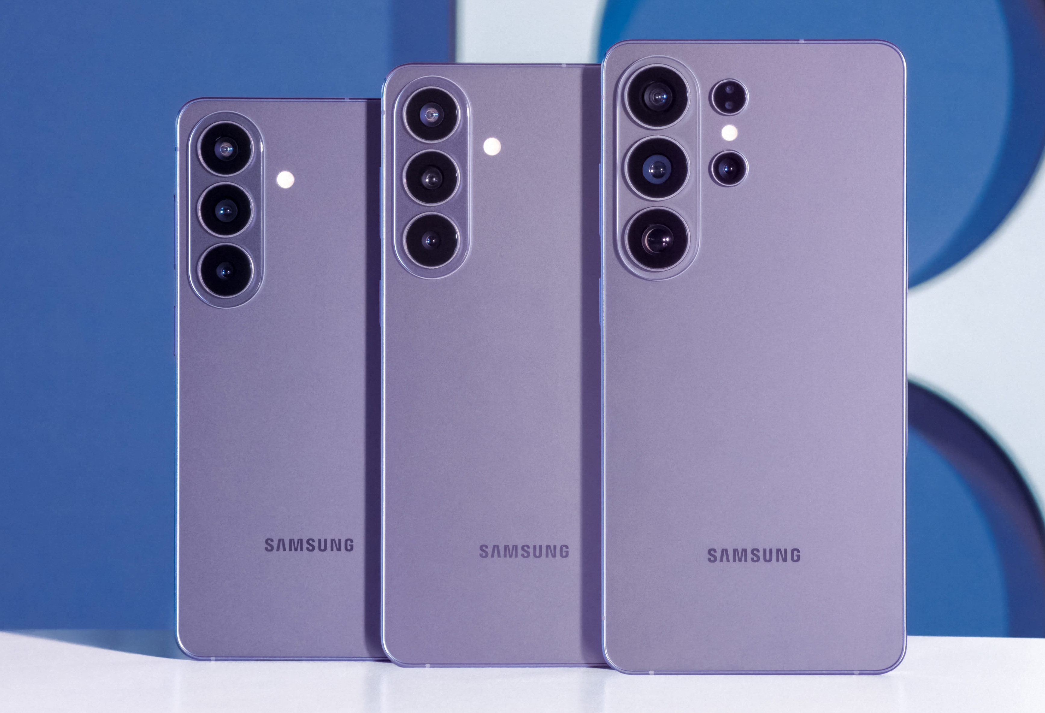 Trzy fioletowe telefony Samsung obok siebie, pokazujące tylne aparaty.
