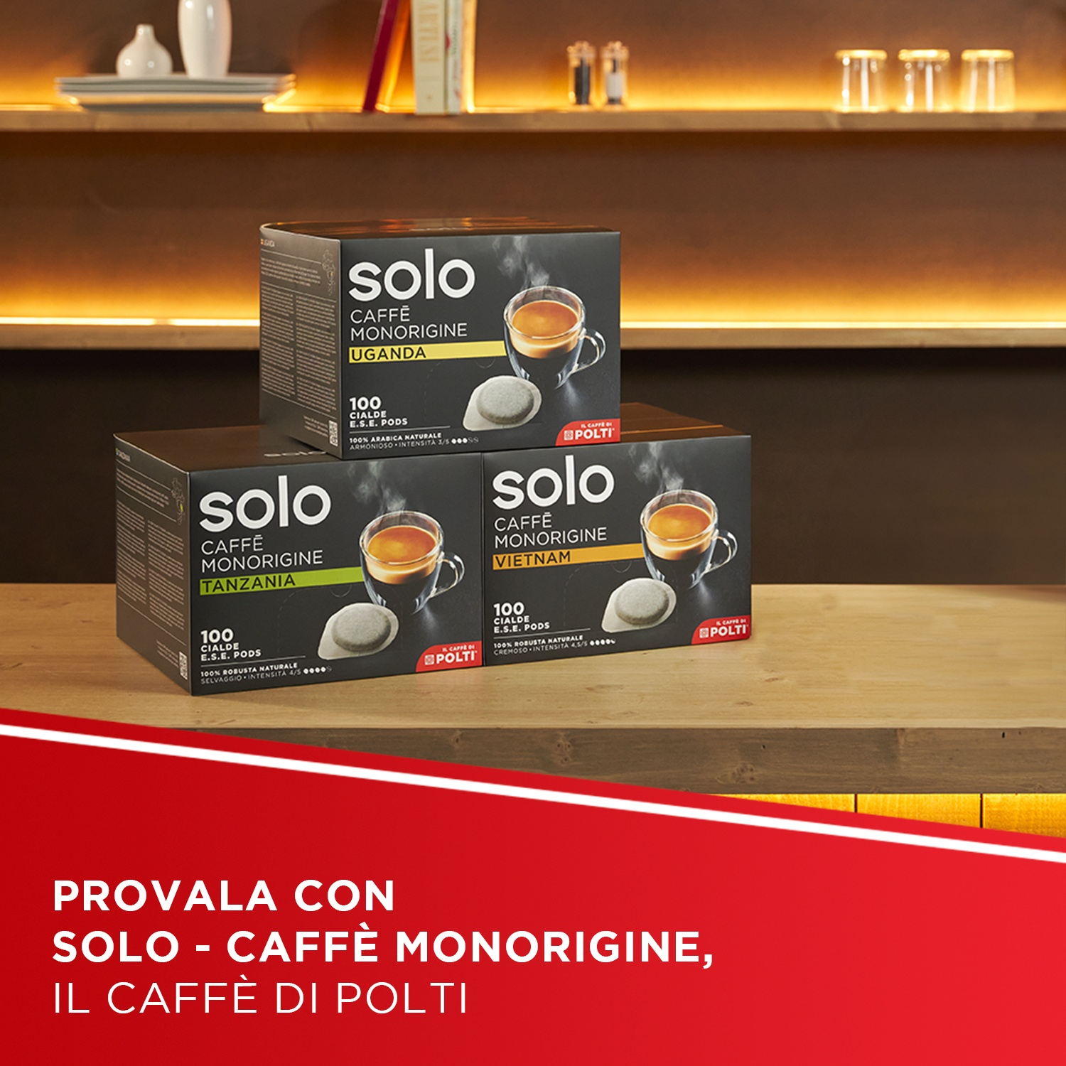 Tre confezioni di caffè Solo con tazzine da espresso. Scaffali chiari sullo sfondo.