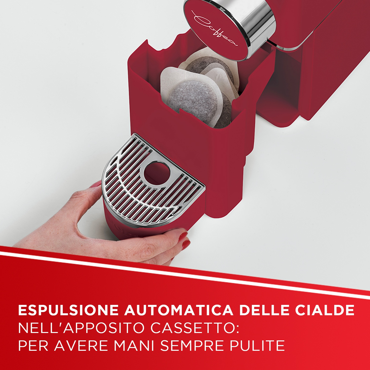 Una macchina da caffè rossa con un cassetto pieno di cialde e una mano che tiene una vaschetta raccogligocce.