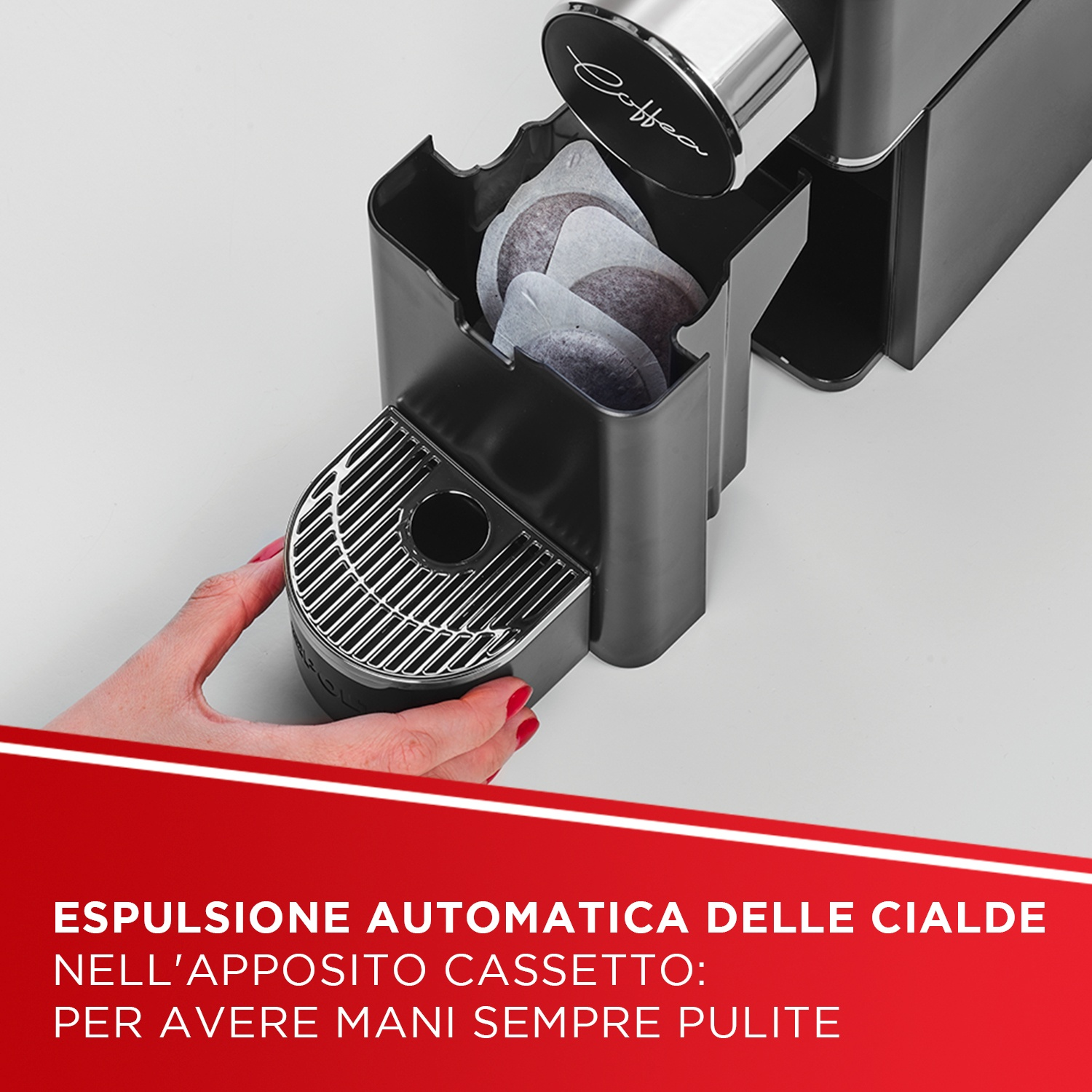 Macchina da caffè con cassetto capsule e capsule di caffè. Una mano tiene il cassetto.