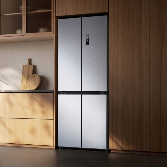 Srebrna, czterodrzwiowa lodówka w drewnianej kuchni.