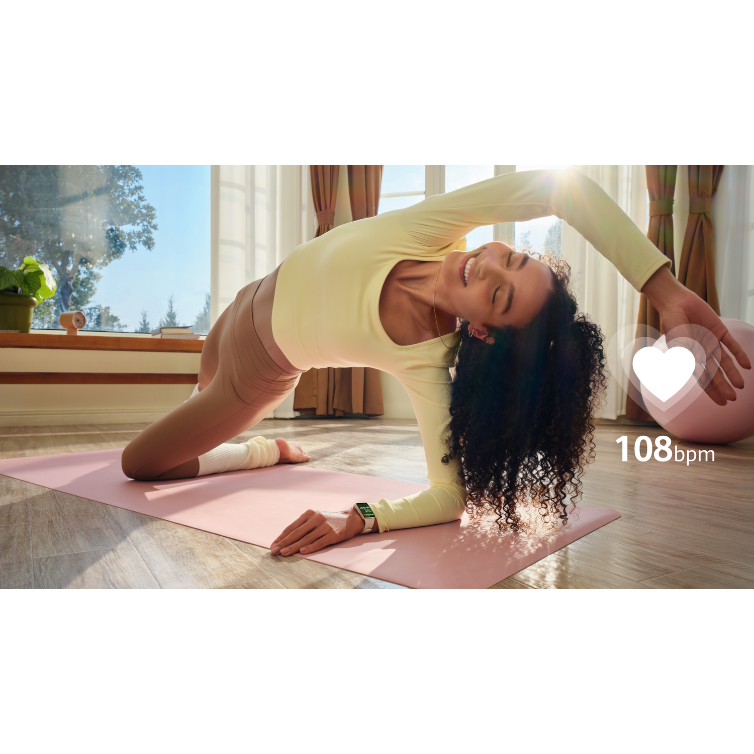 Femme en haut jaune et legging beige faisant du yoga sur tapis rose.