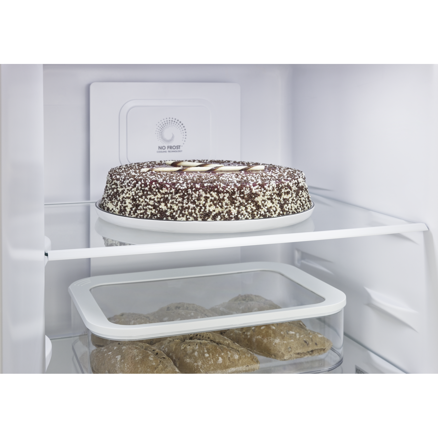 Een chocoladetaart staat op een plank boven brood in een bak.