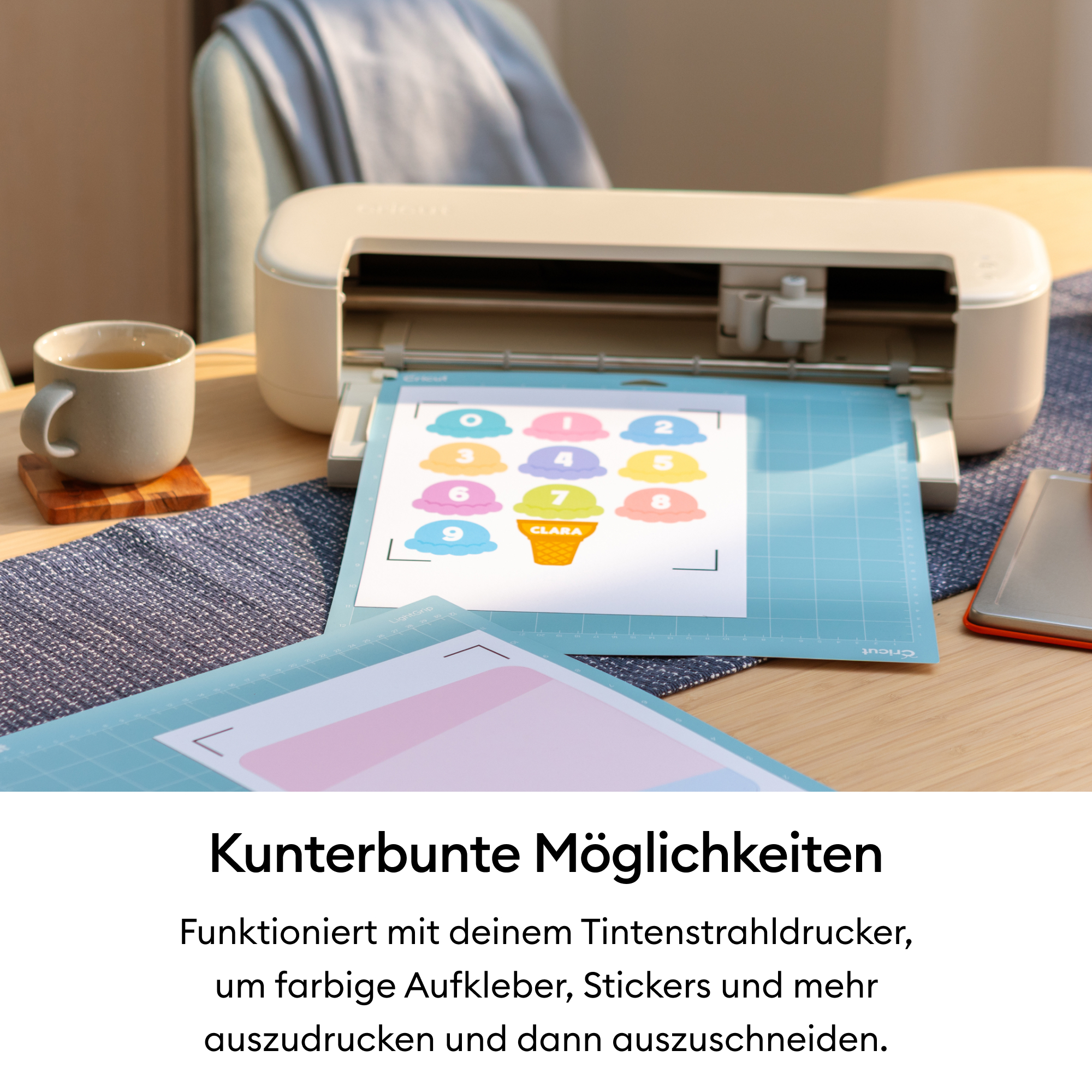 Ein Schneidegerät mit bunten Aufklebern und einer Tasse Tee auf einem Tisch.