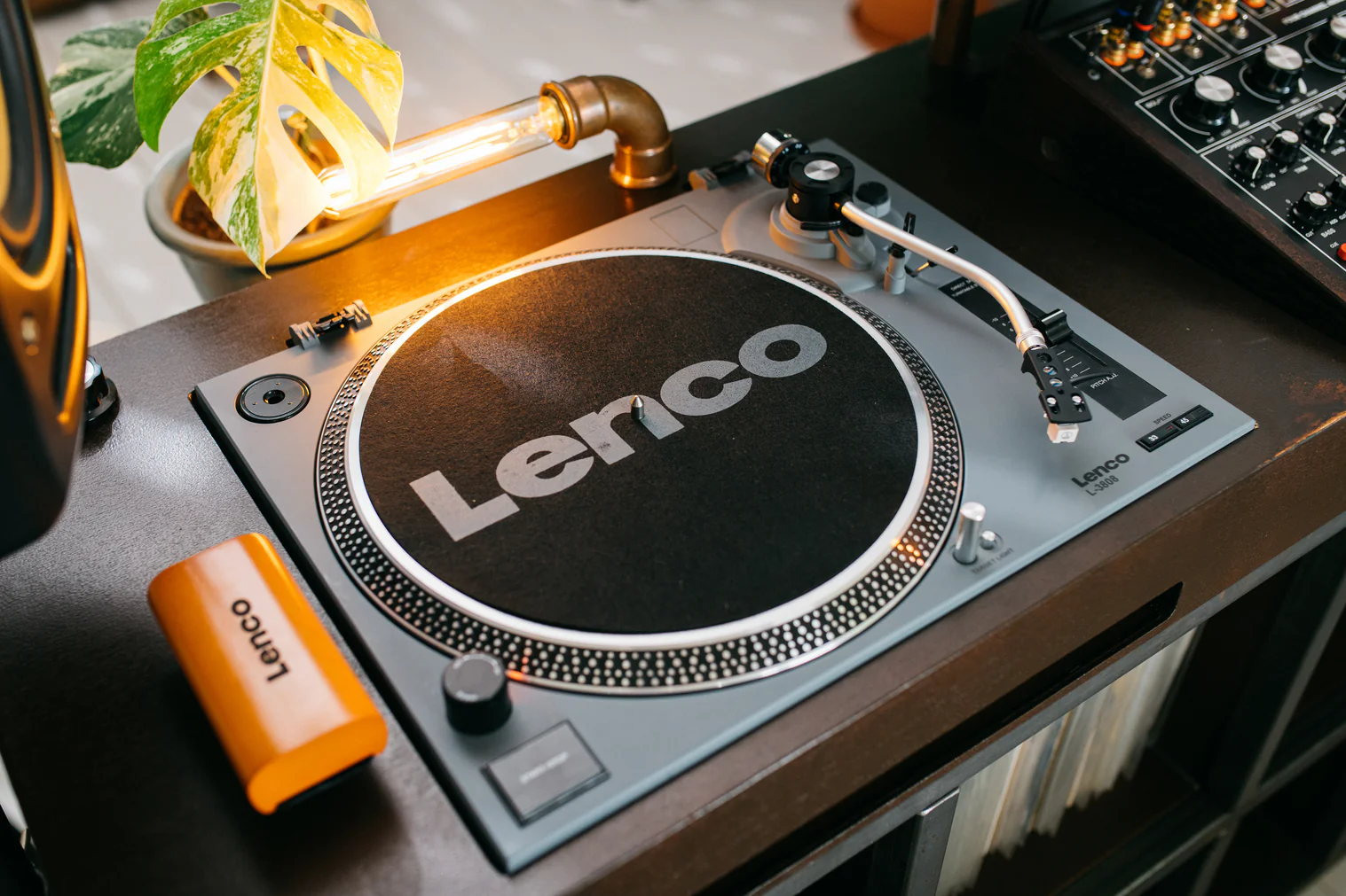 Ein Plattenspieler mit "Lenco"-Logo, daneben eine orangefarbene Lenco-Box.