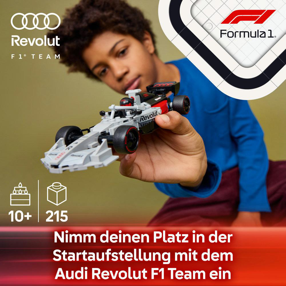 Ein Junge hält einen grauen Formel-1-Wagen von Audi Revolut mit roten Akzenten.